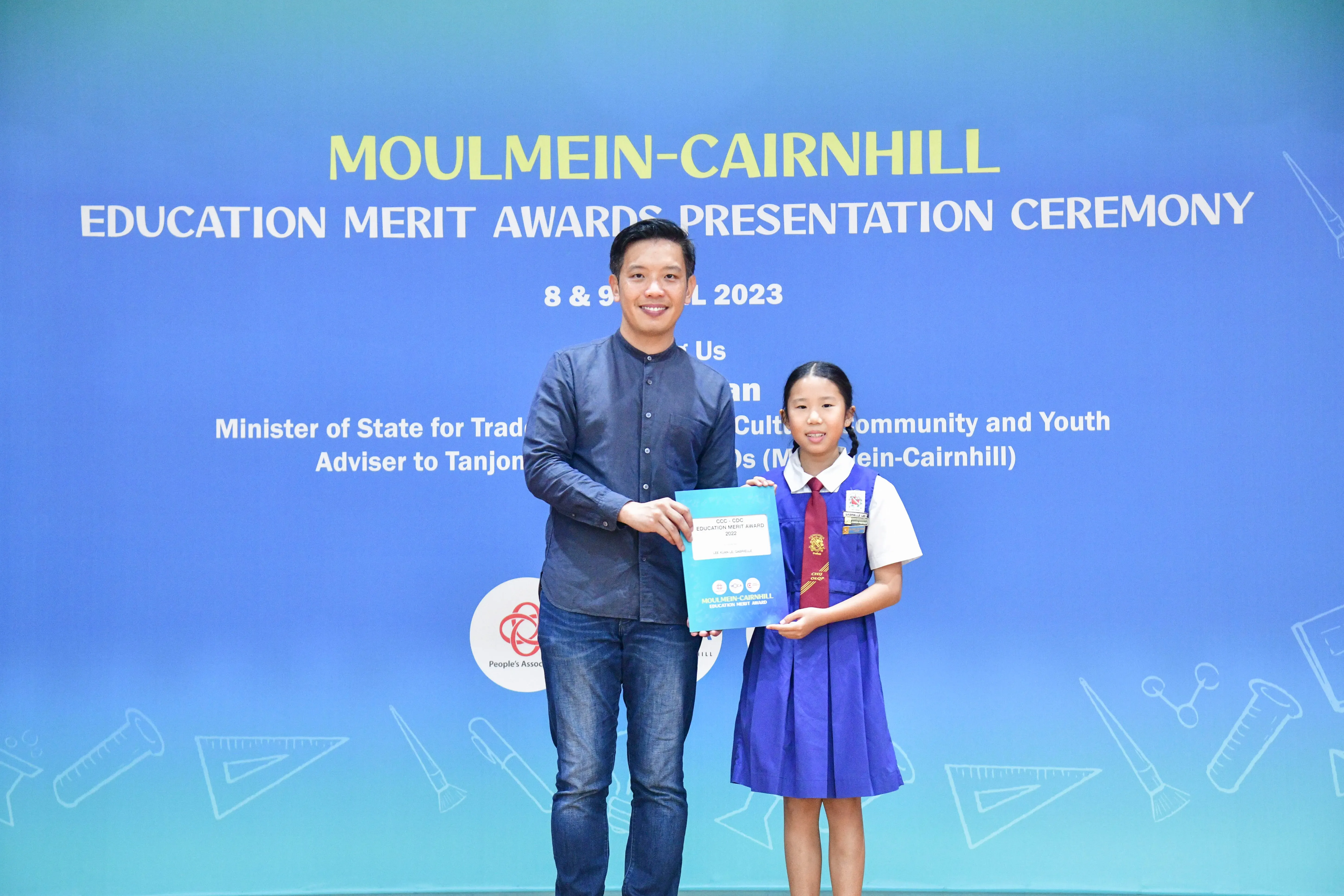 A man and a young girl in school uniform hold an award certificate at the Moulmein-Cairnhill Education Merit Awards 2023.