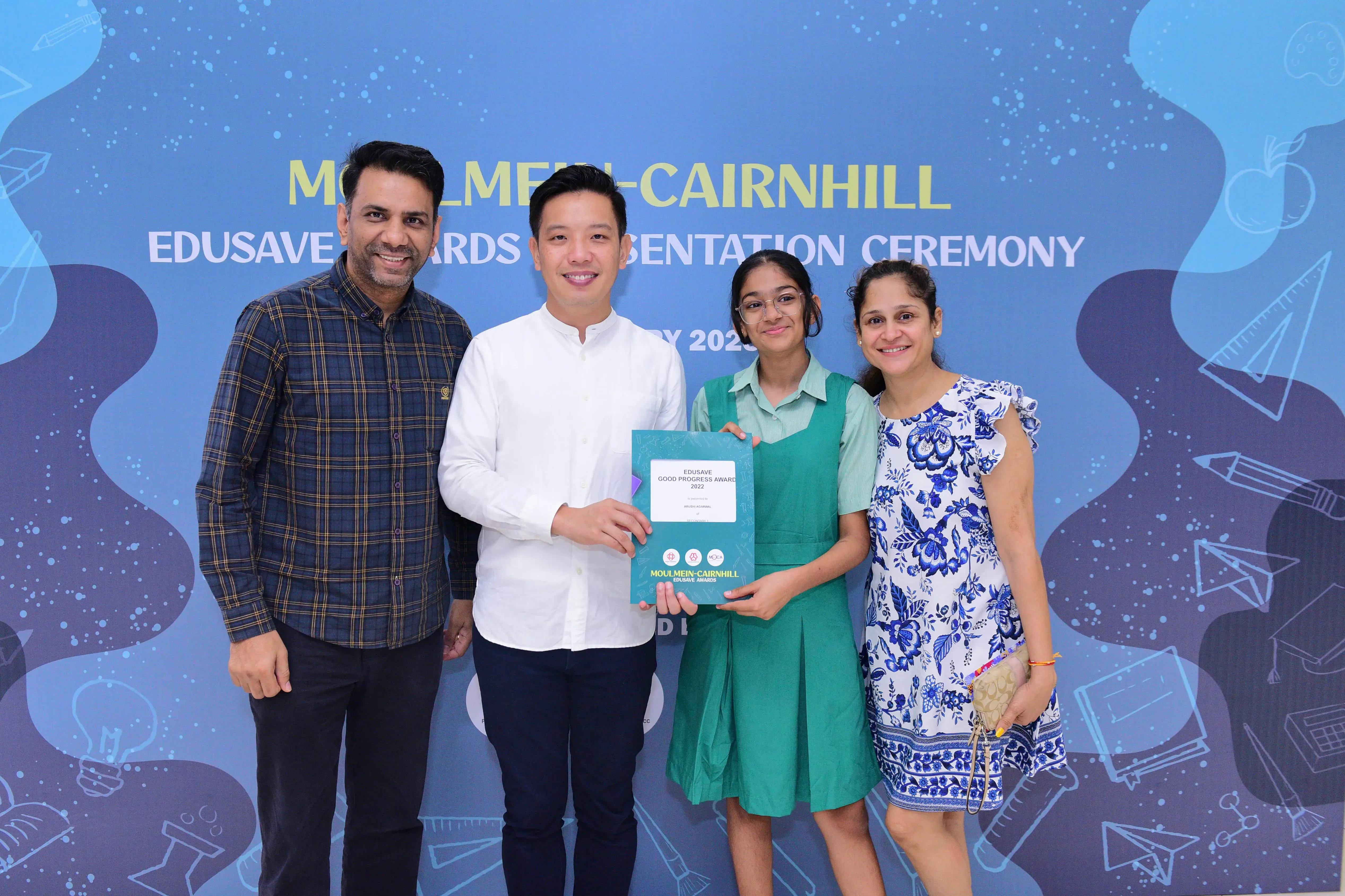 Four people smile holding an Edusave award at the Moulmein-Cairnhill Edusave Awards Presentation Ceremony.