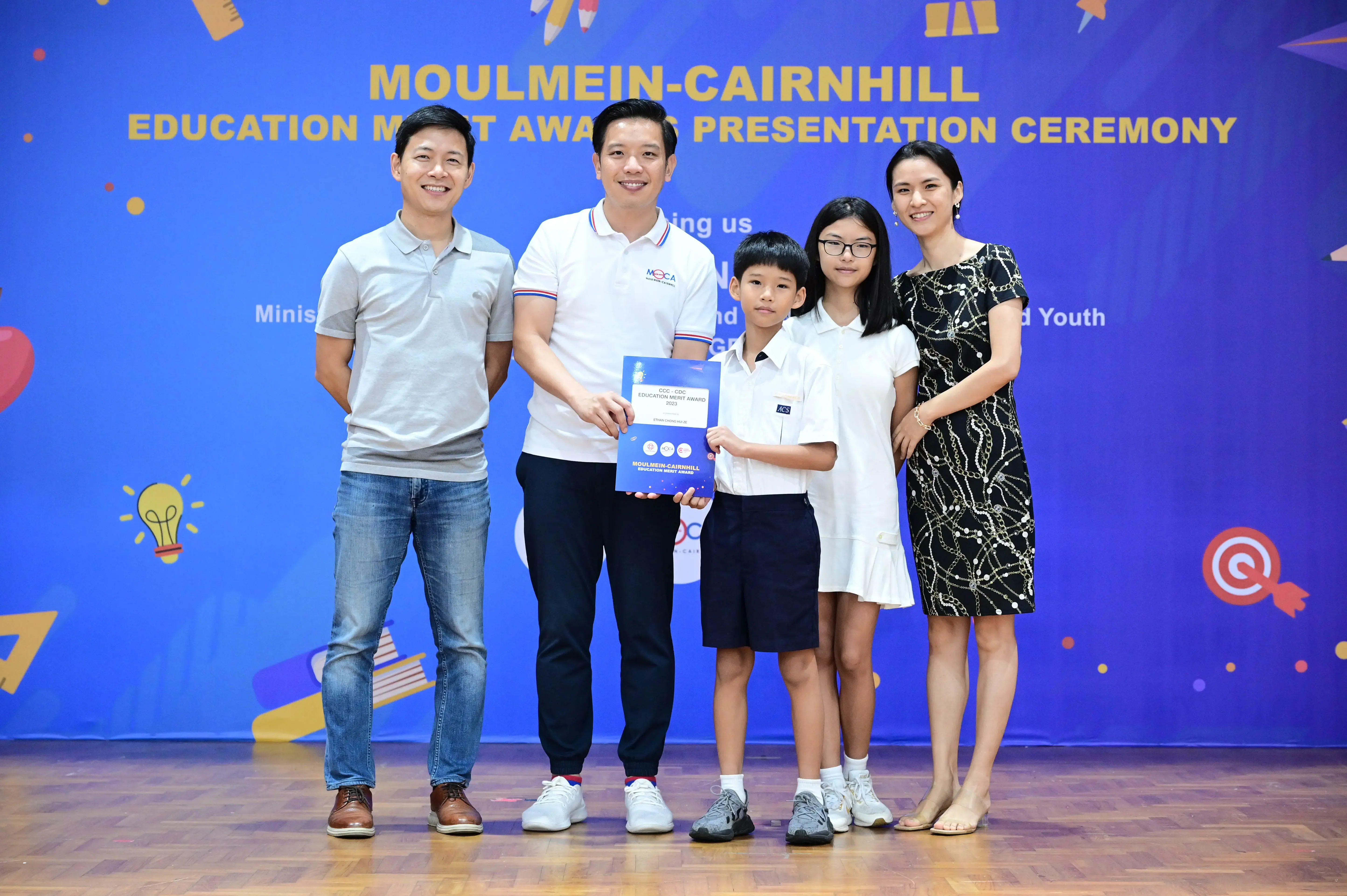 Five people pose with a certificate at the Moulmein-Cairnhill Education Merit Awards Presentation Ceremony.