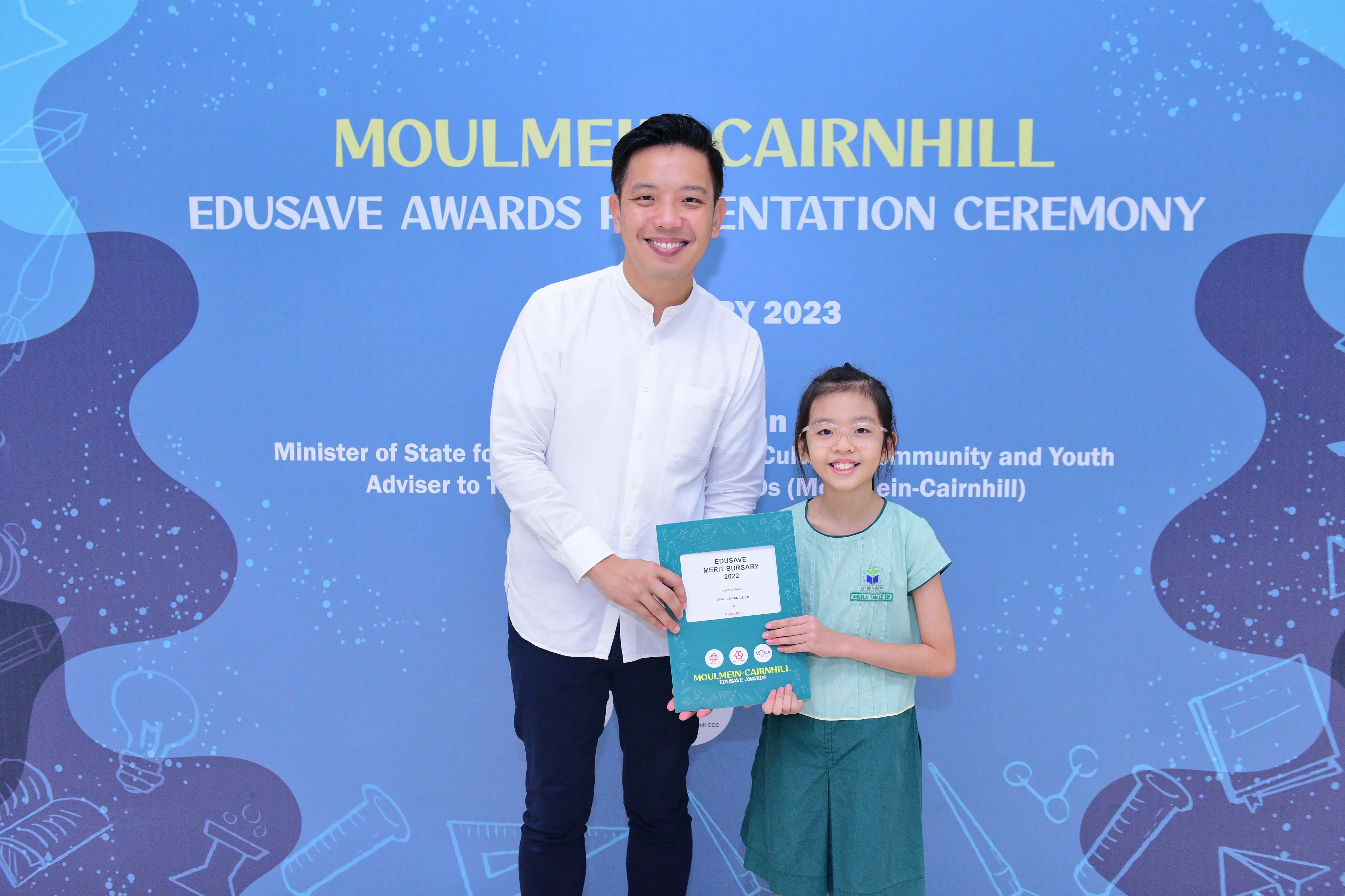 Man and young girl hold an Edusave Merit Bursary certificate at the Moulmein-Cairnhill Edusave Awards Ceremony 2023.