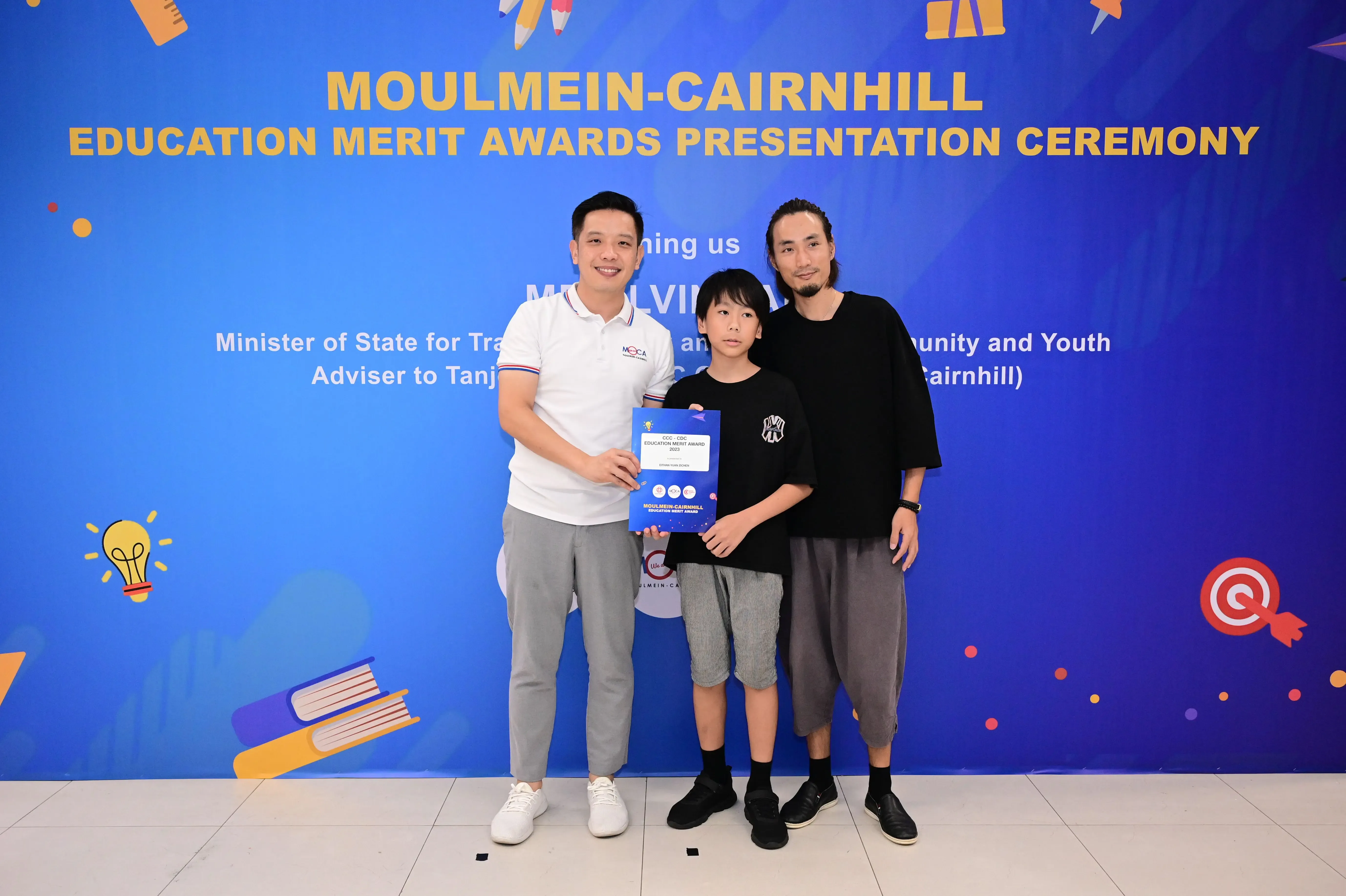 Three people pose with an award certificate at the Moulmein-Cairnhill Education Merit Awards Presentation Ceremony.