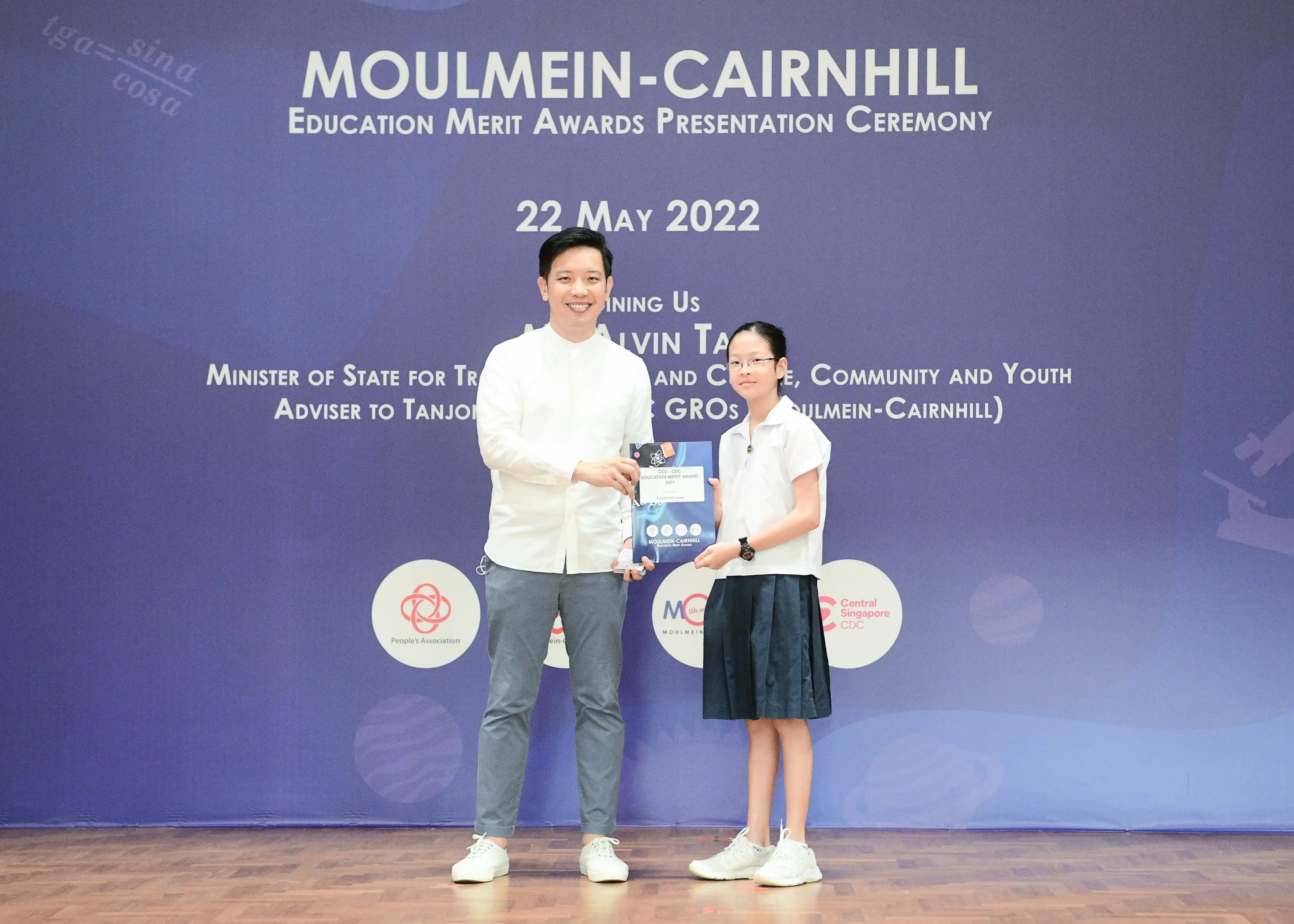 A man and a young girl hold an award together at the Moulmein-Cairnhill Education Merit Awards ceremony on 22 May 2022.