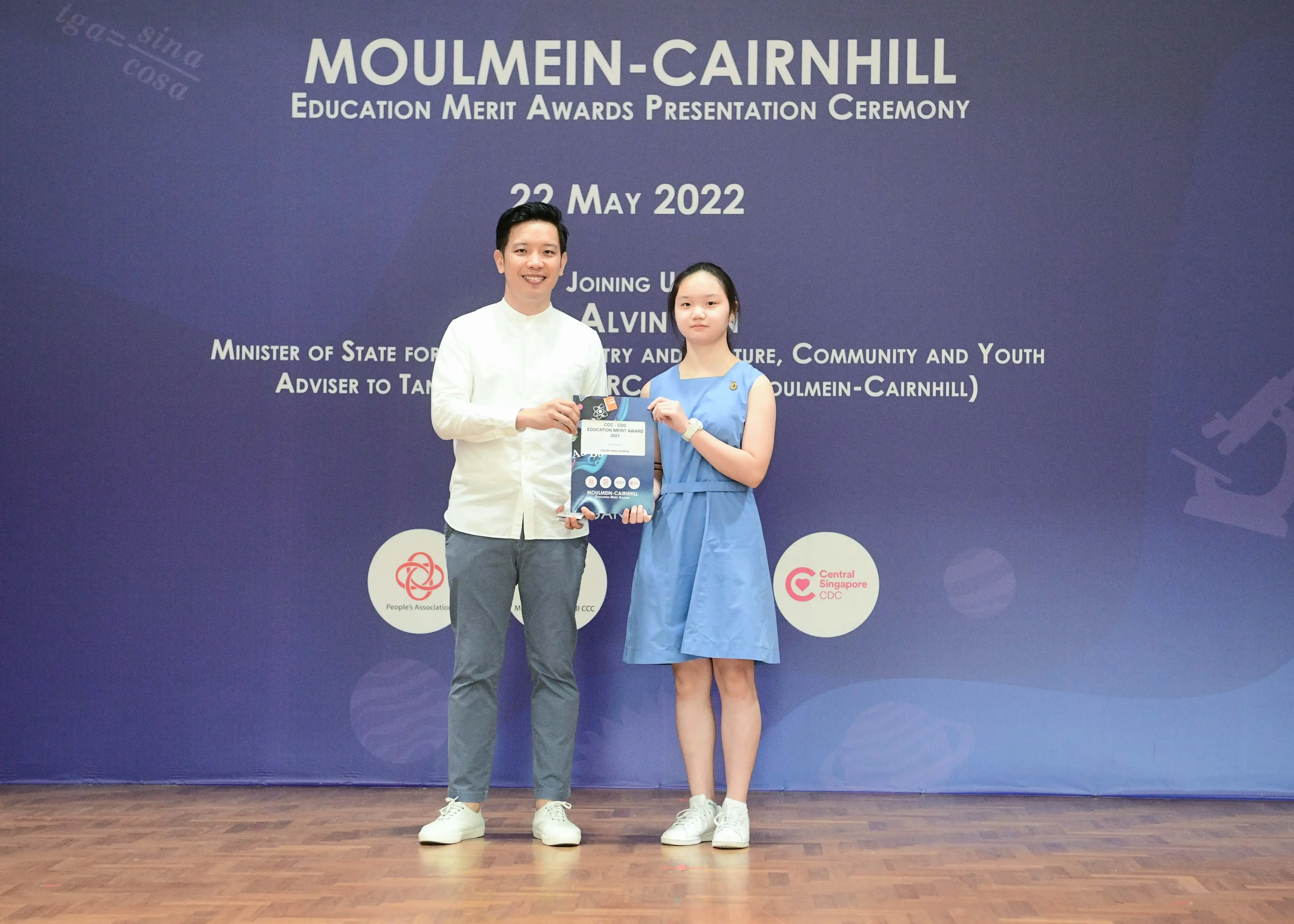 Two people hold an award certificate at the Moulmein-Cairnhill Education Merit Awards Ceremony on 22 May 2022.