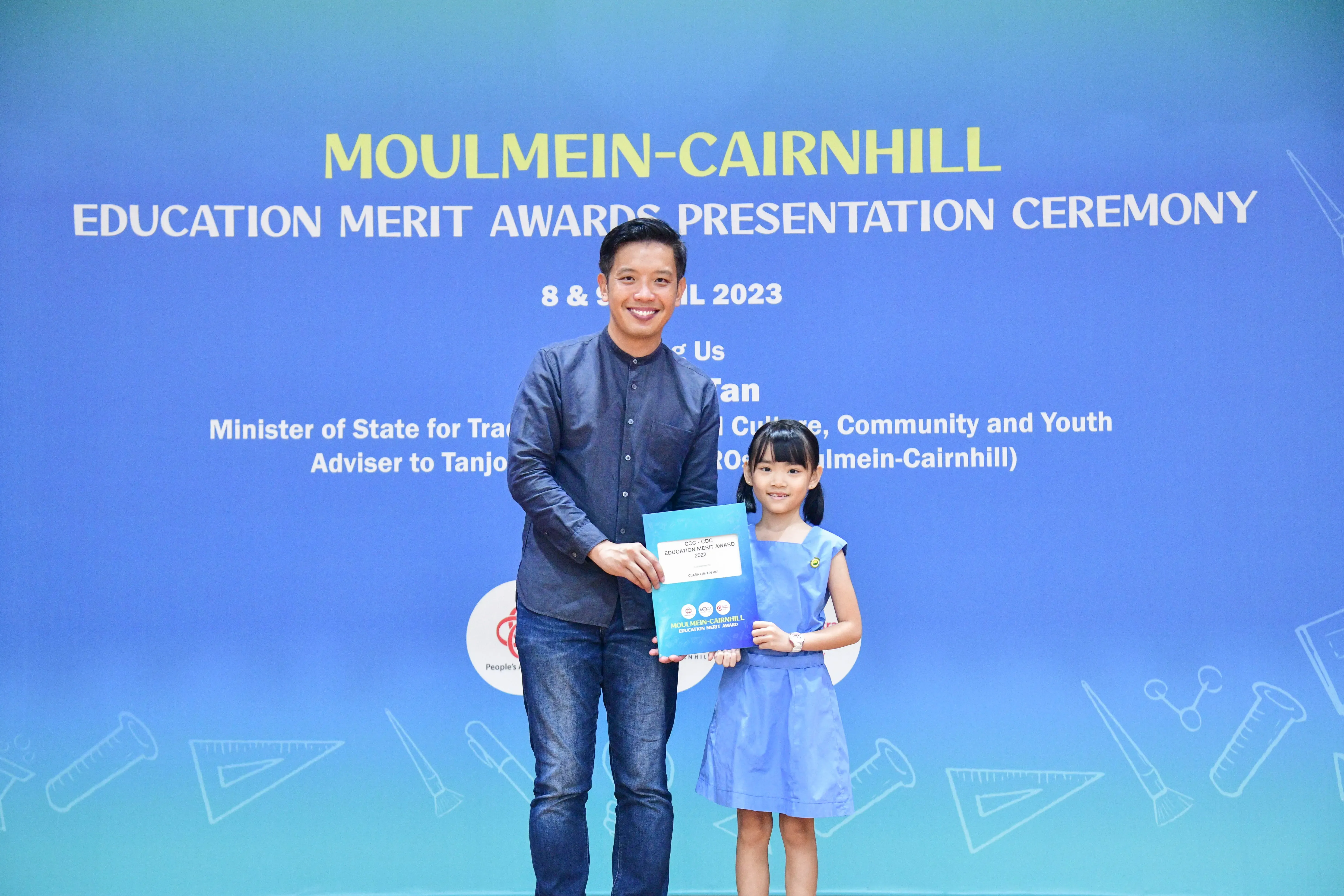 A man and a young girl hold an award together at the Moulmein-Cairnhill Education Merit Awards Ceremony 2023.