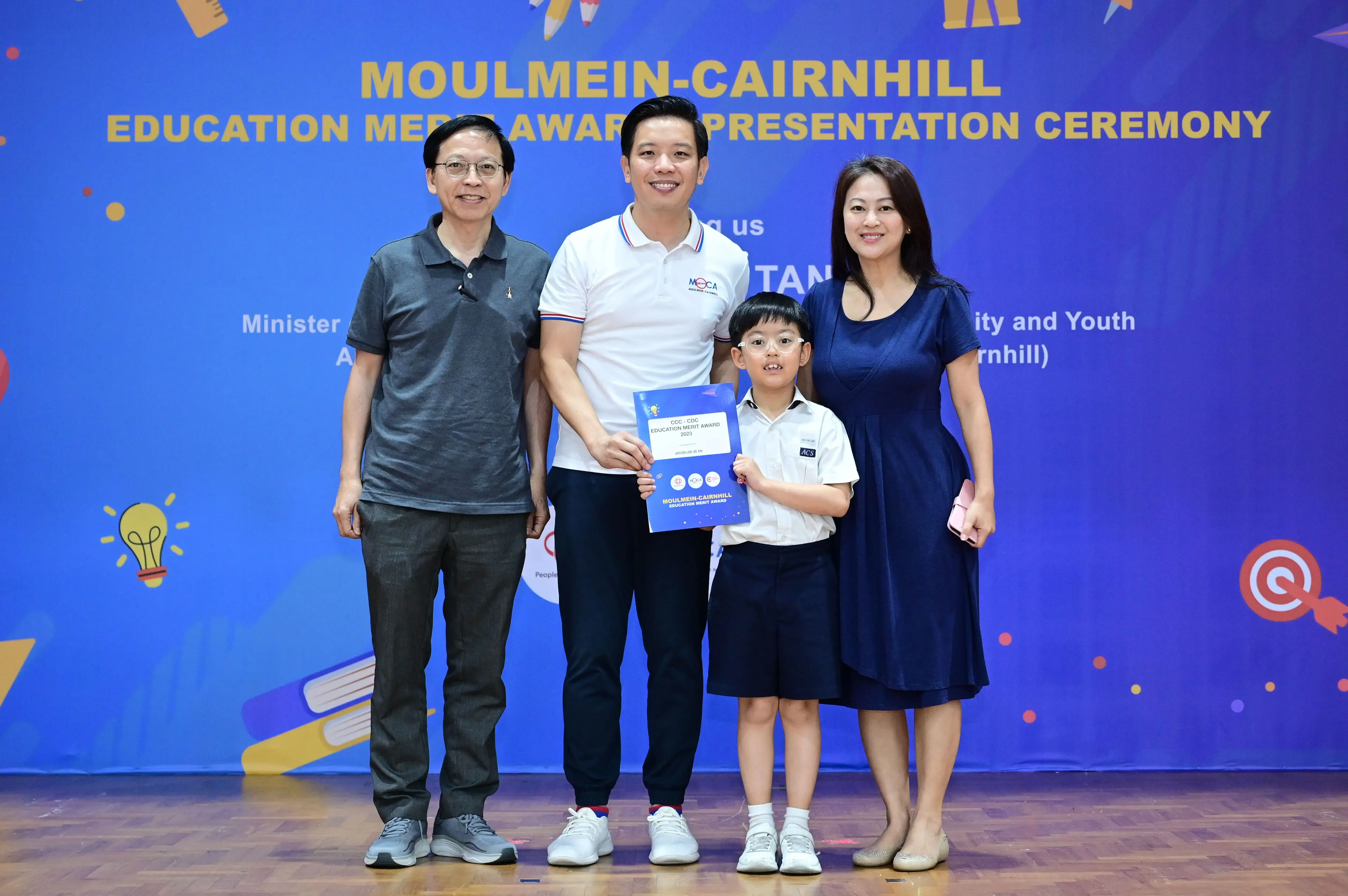Three adults and a young boy holding a certificate pose at the Moulmein-Cairnhill Education Merit Award Ceremony.