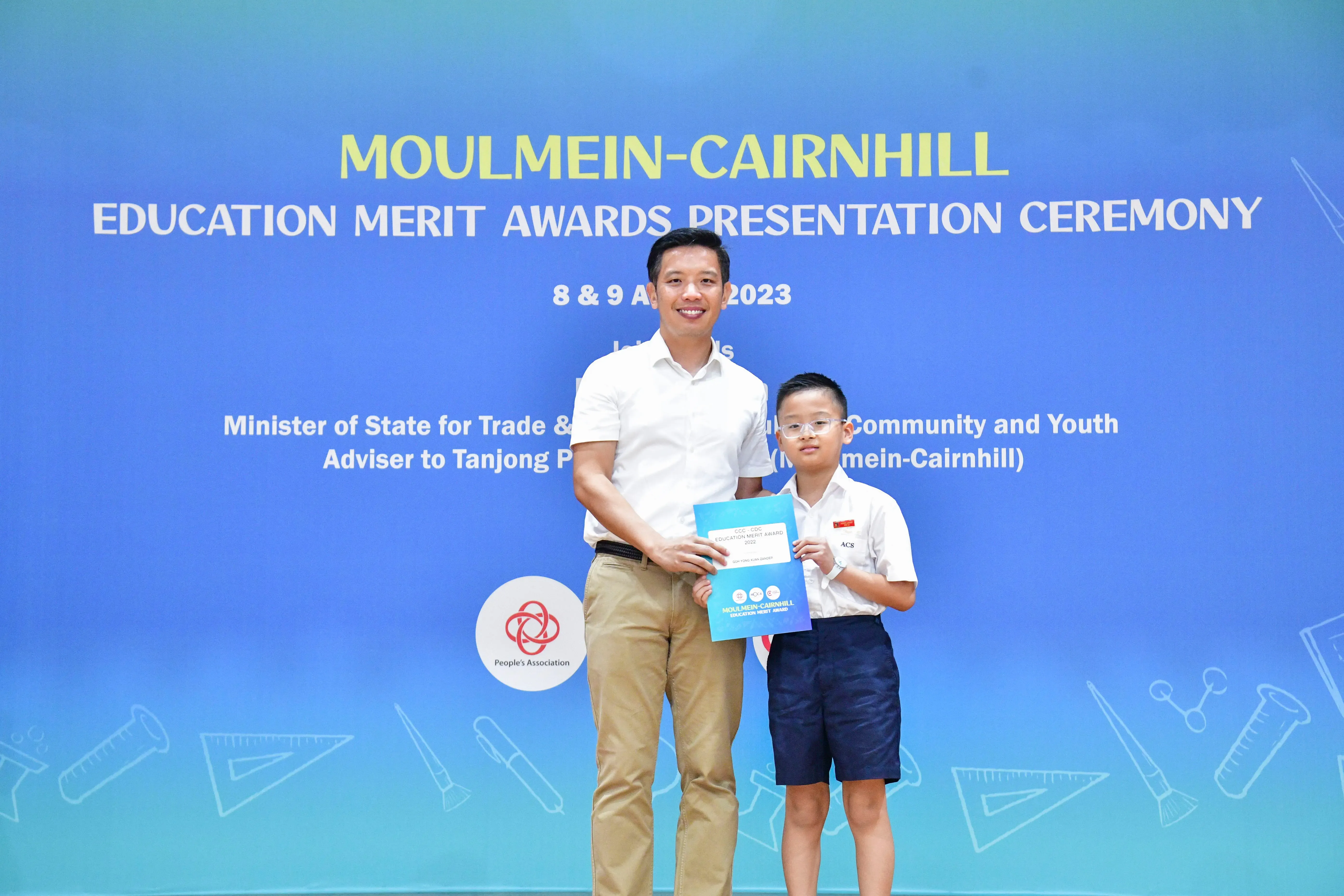 Adult man and young boy holding an award certificate at Moulmein-Cairnhill Education Merit Awards 2023.