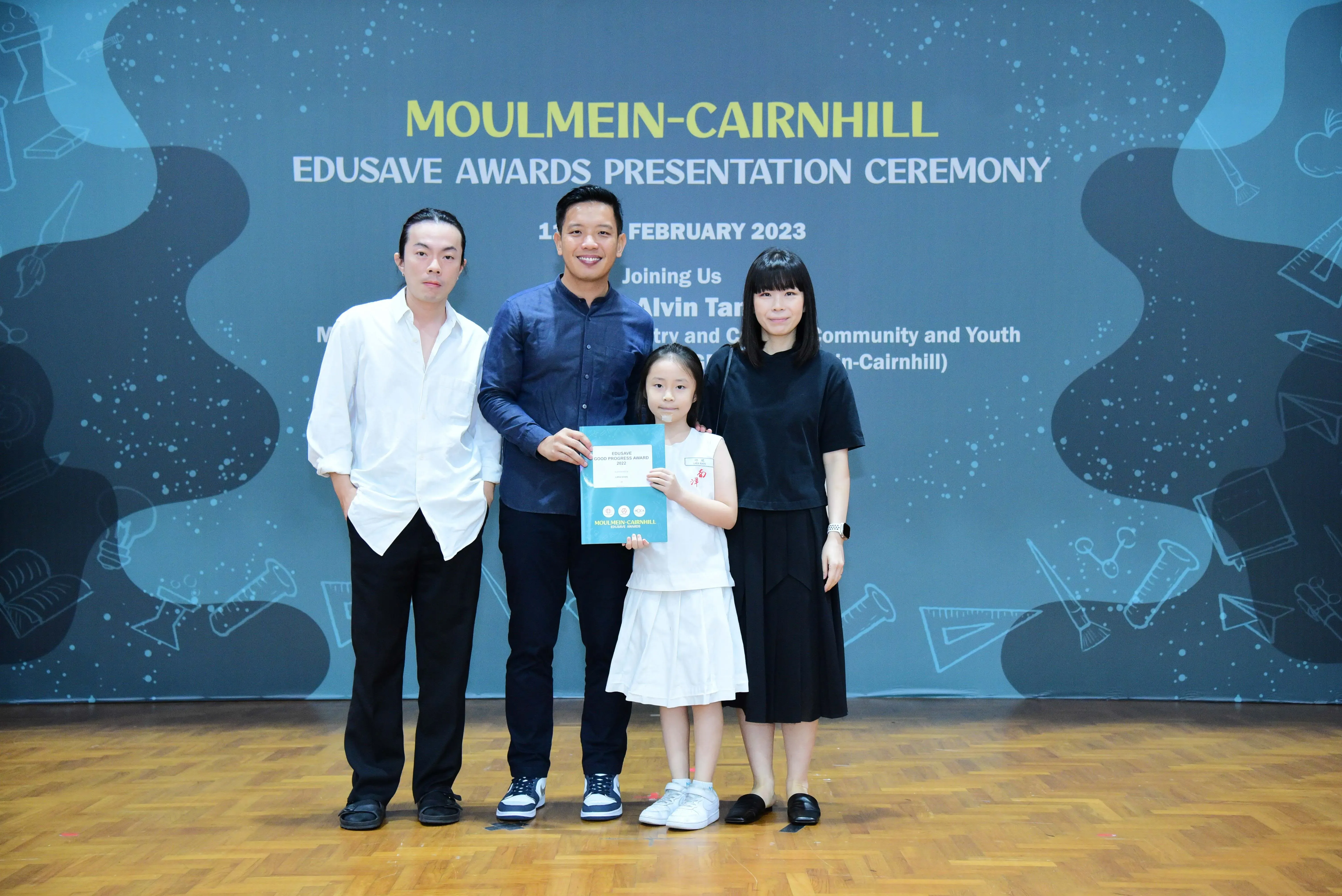 Three adults and a young girl pose holding an award at the Moulmein-Cairnhill Edusave Awards Ceremony, February 2023.