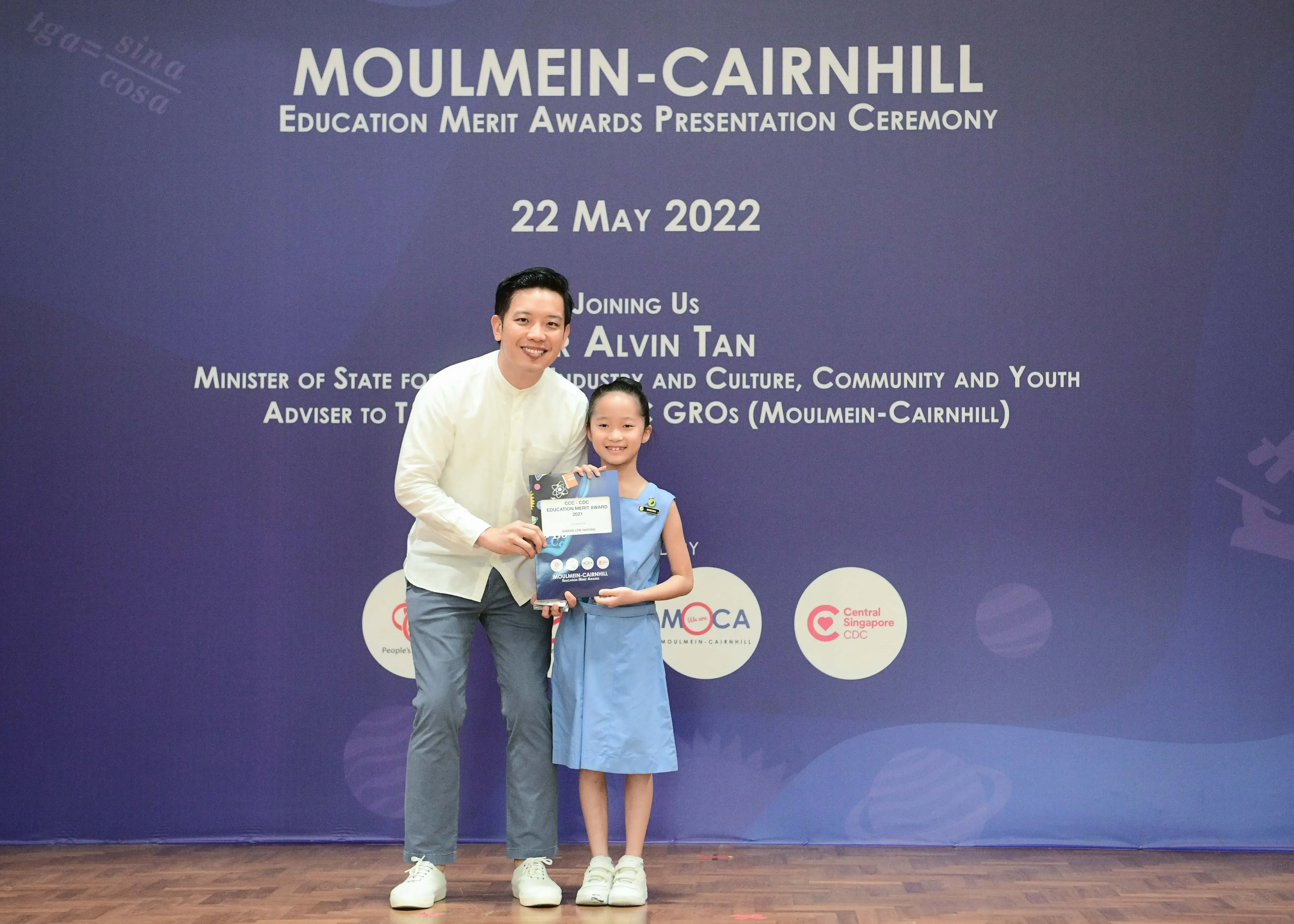 A man and a young girl hold an award certificate at the Moulmein-Cairnhill Education Merit Awards Ceremony on 22 May 2022.