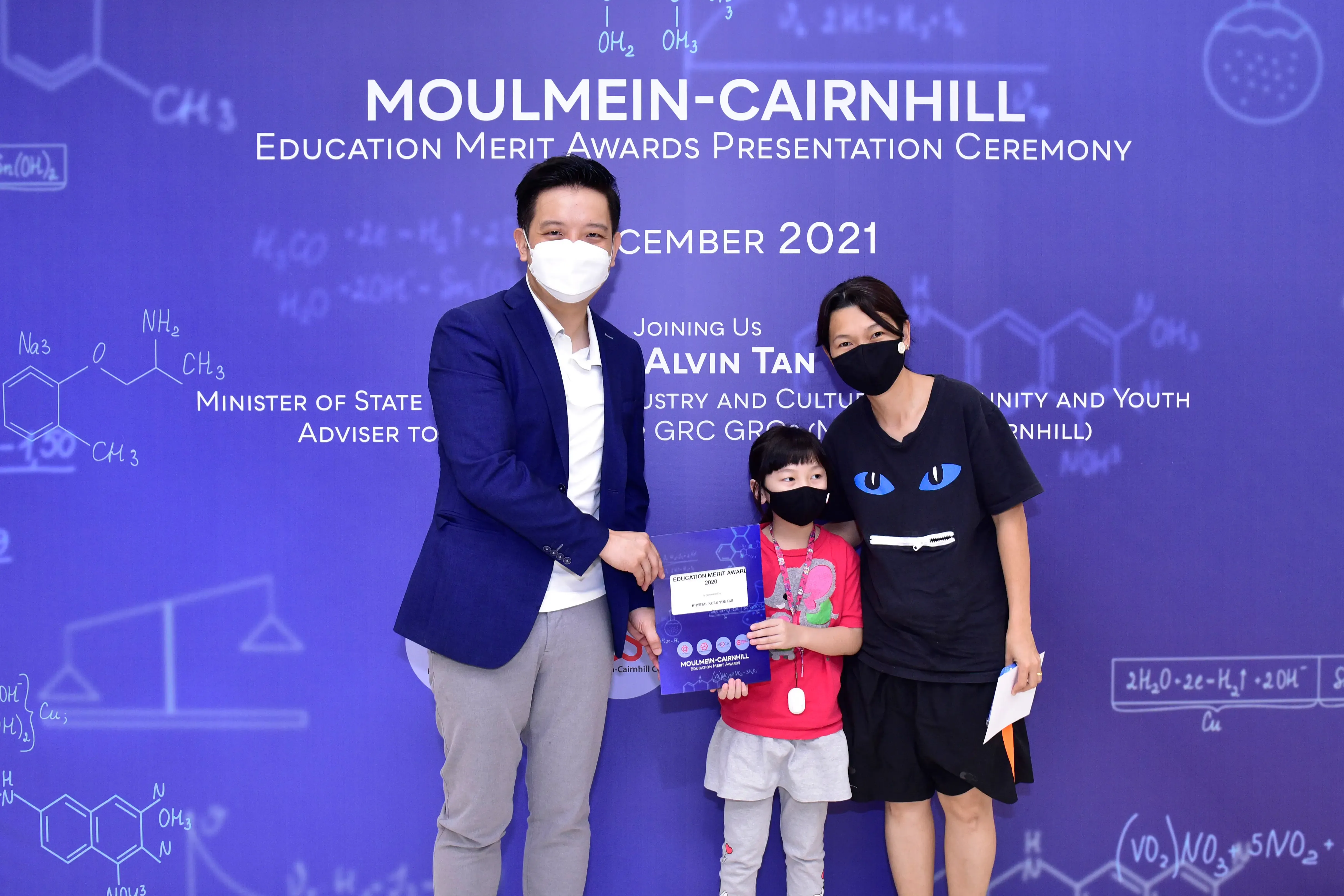 Three masked people pose at the Moulmein-Cairnhill Education Merit Awards Ceremony in December 2021.