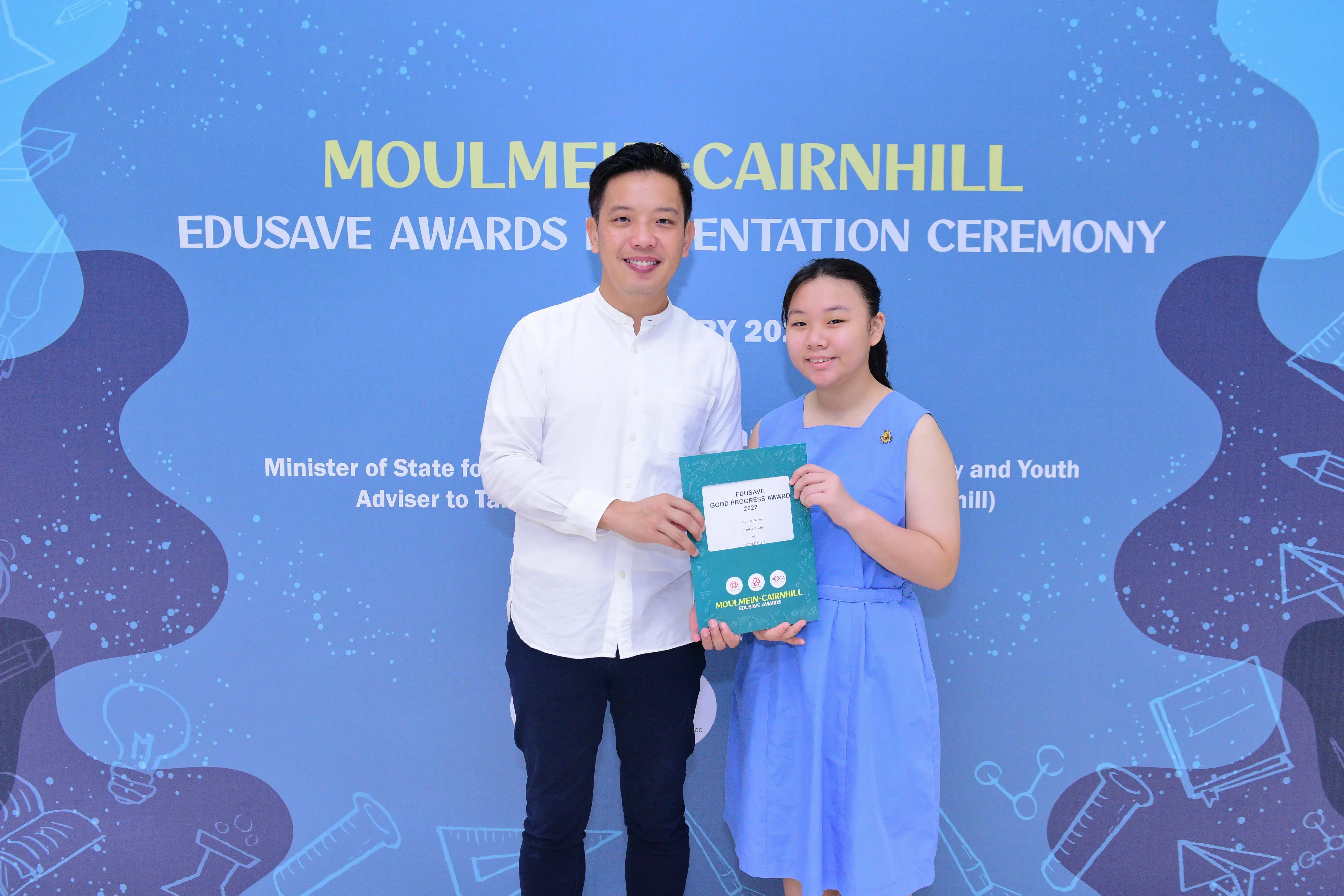 A man and a girl holding an Edusave Good Progress Award certificate at the Moulmein-Cairnhill Awards Ceremony.