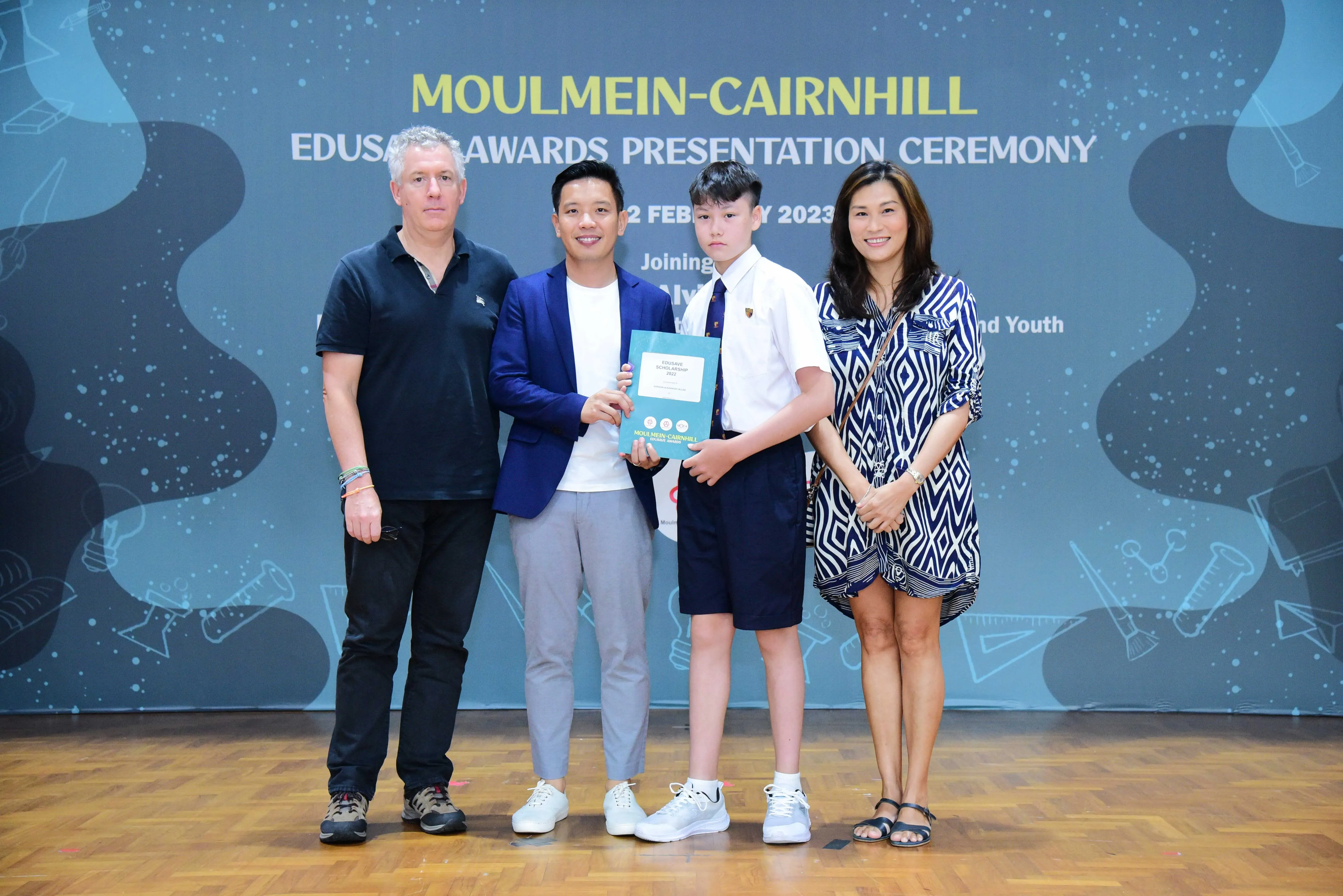 Four people pose at the Moulmein-Cairnhill Edusave Awards Presentation Ceremony 2023, holding a certificate.
