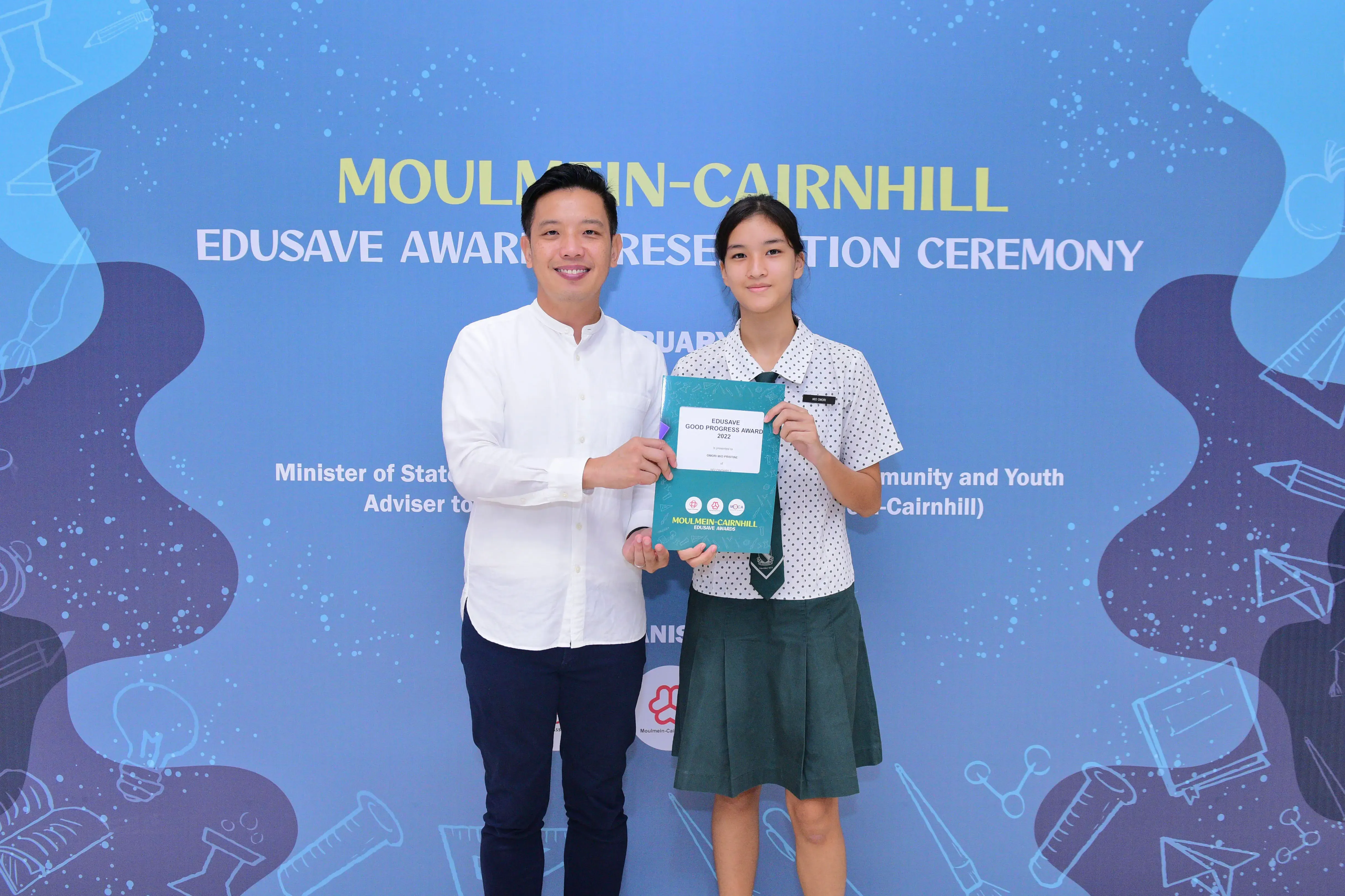 A man and a teenage girl hold an Edusave Good Progress Award certificate at the Moulmein-Cairnhill ceremony.