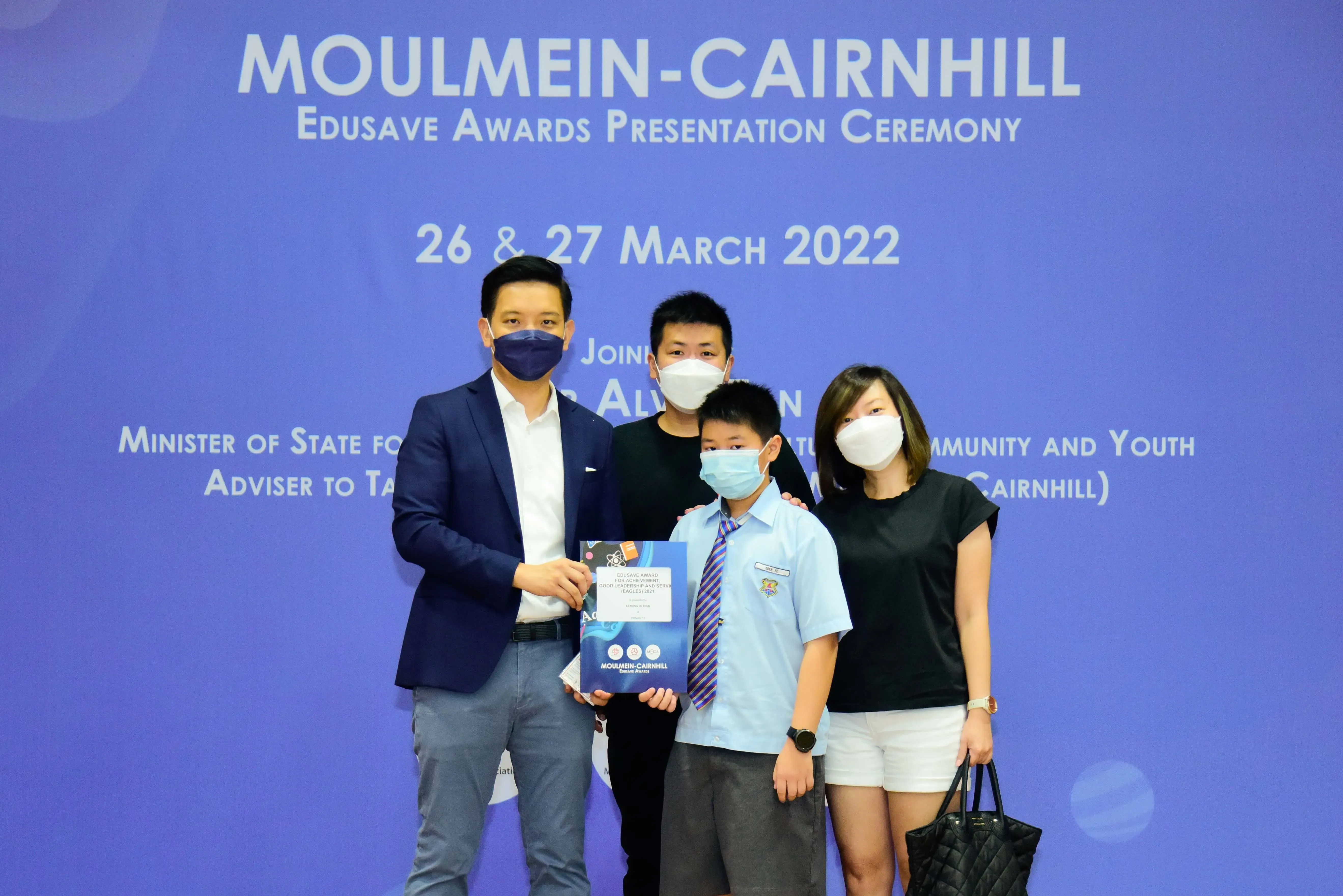 Four masked people pose at the Moulmein-Cairnhill Edusave Awards Presentation Ceremony on 26-27 March 2022.