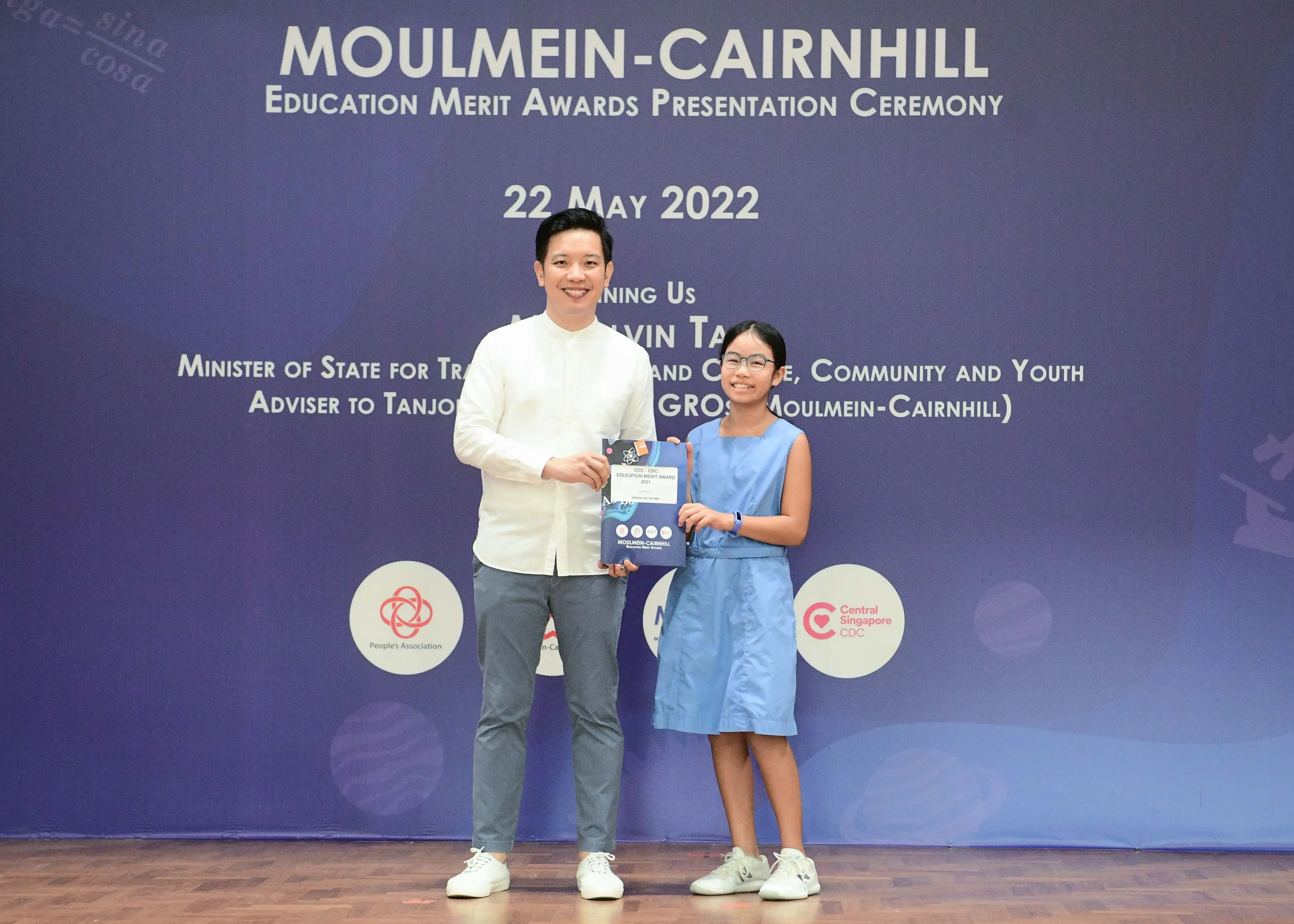 A man and a young girl hold an award certificate at the Moulmein-Cairnhill Education Merit Awards on 22 May 2022.