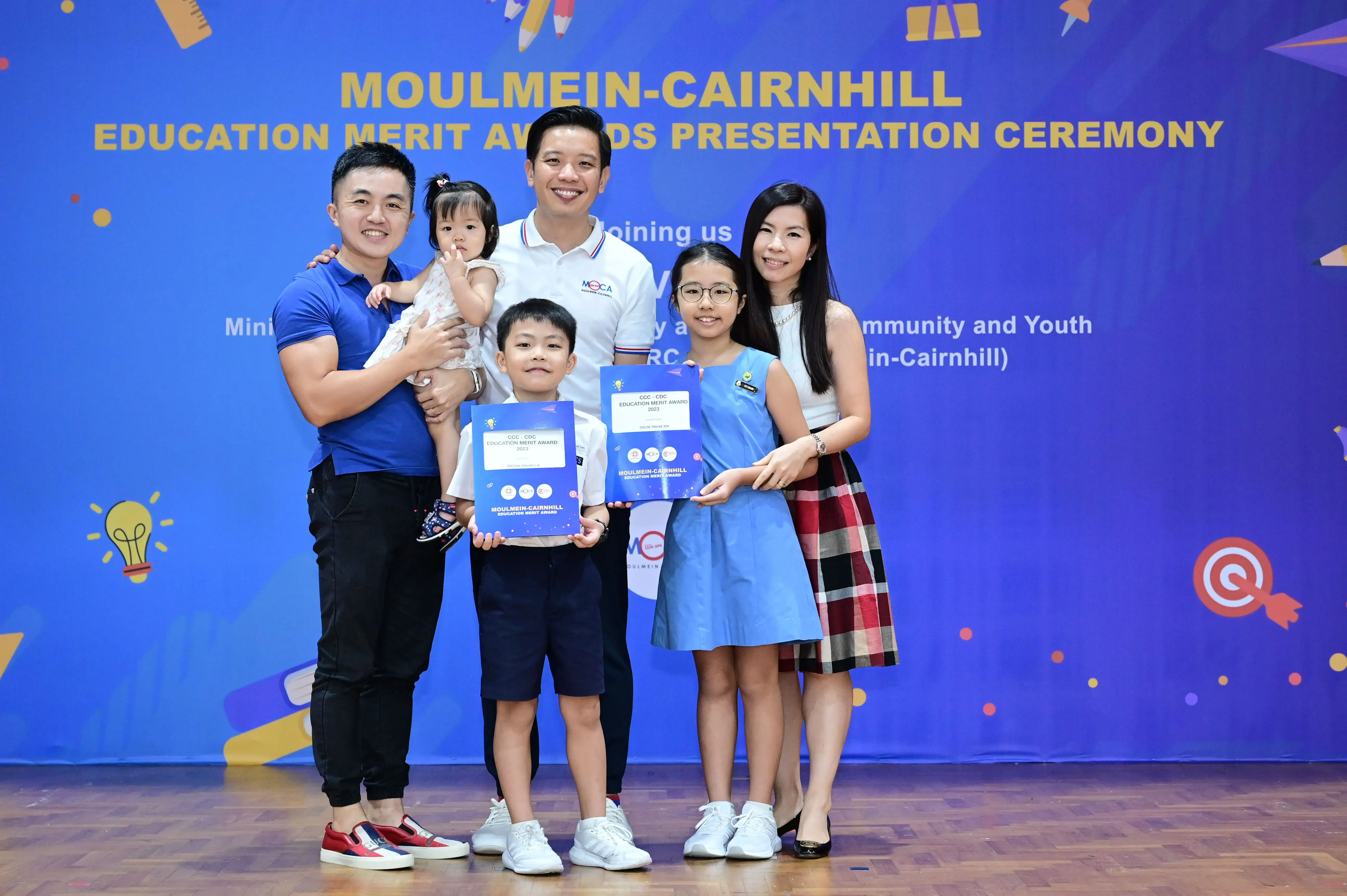Family of five posing with award certificates at Moulmein-Cairnhill Education Merit Awards Presentation Ceremony.