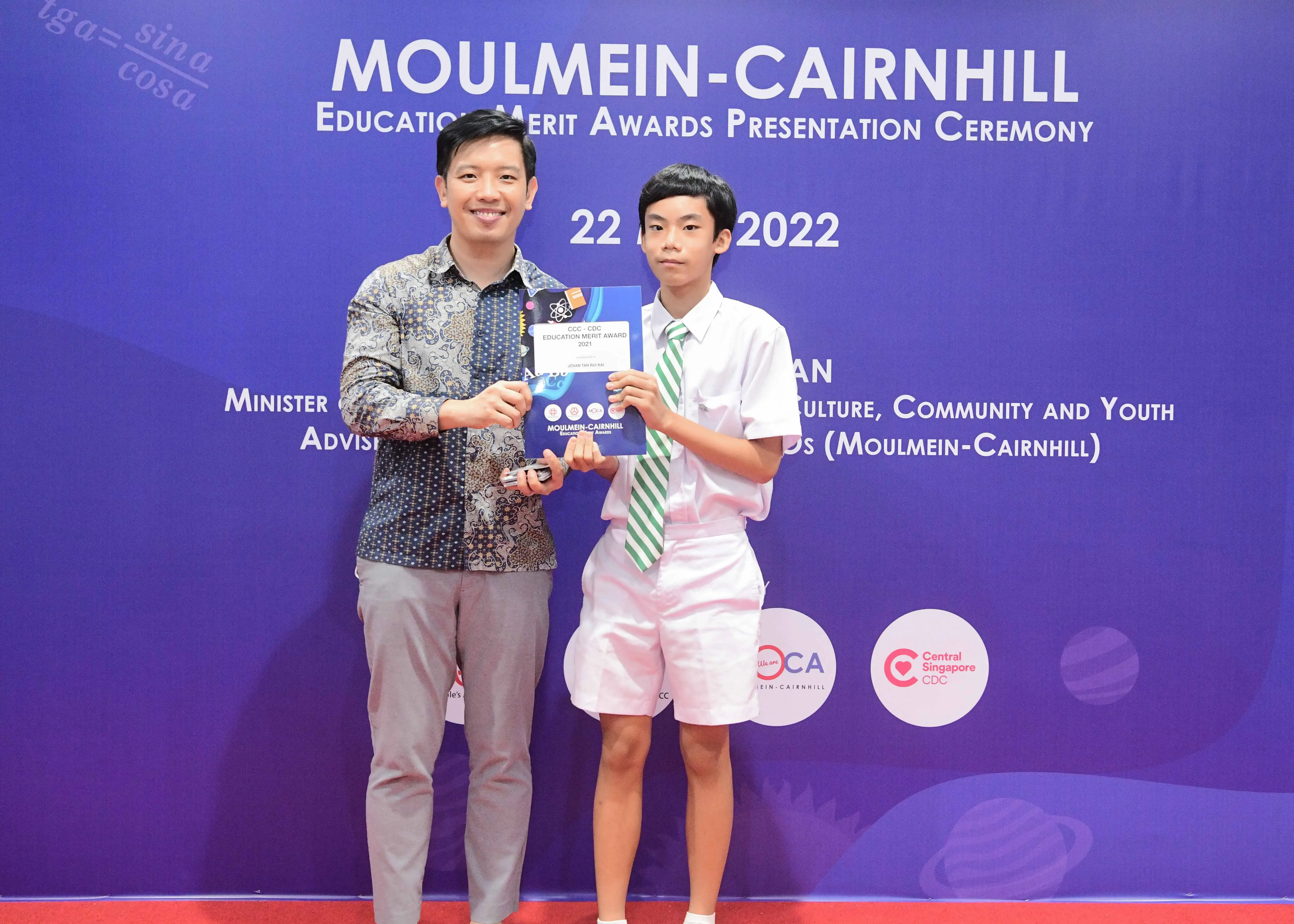 Two people hold an award certificate at the Moulmein-Cairnhill Education Merit Awards Presentation Ceremony 2022.