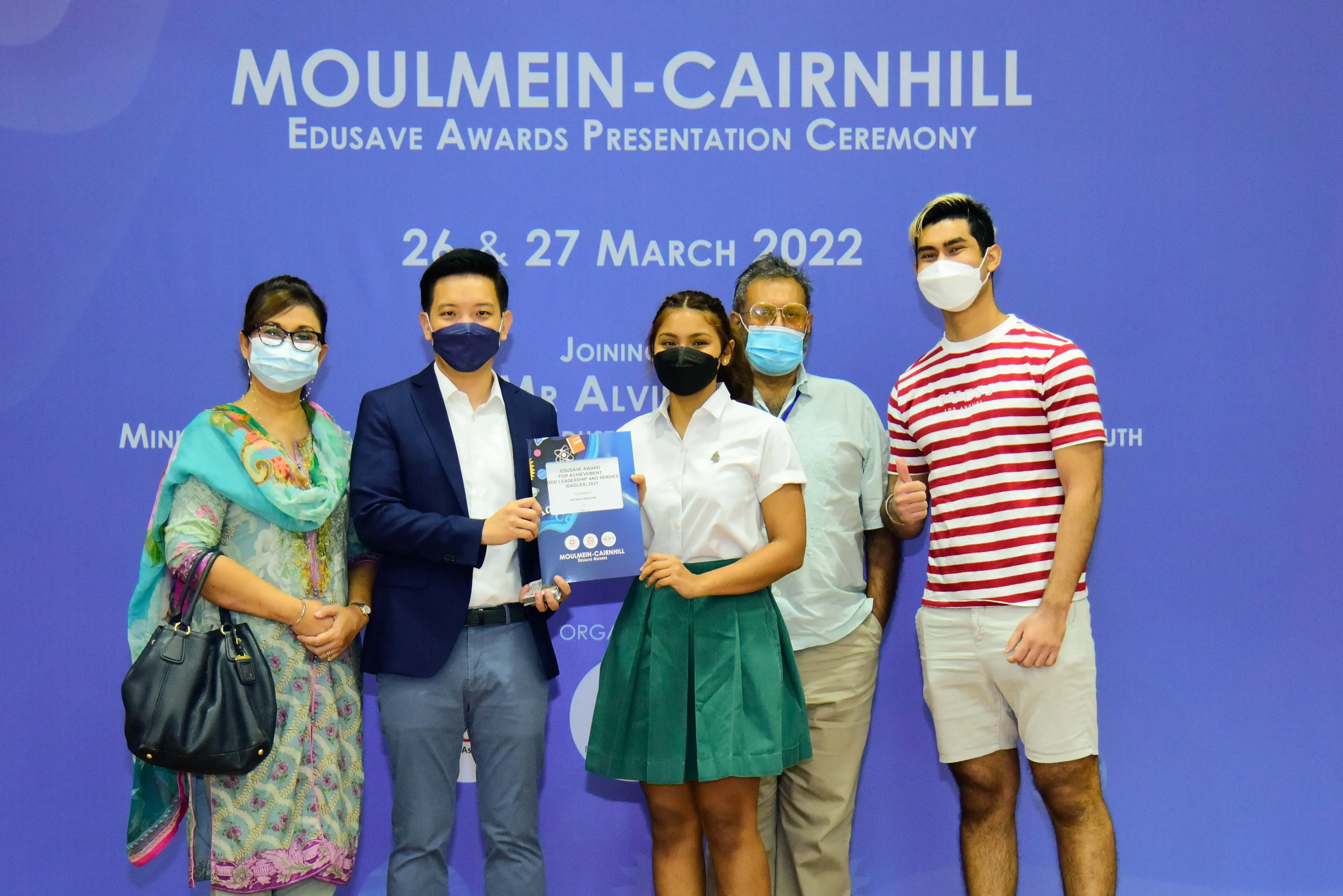 Five masked people pose at the Moulmein-Cairnhill Edusave Awards Presentation Ceremony on 26-27 March 2022.
