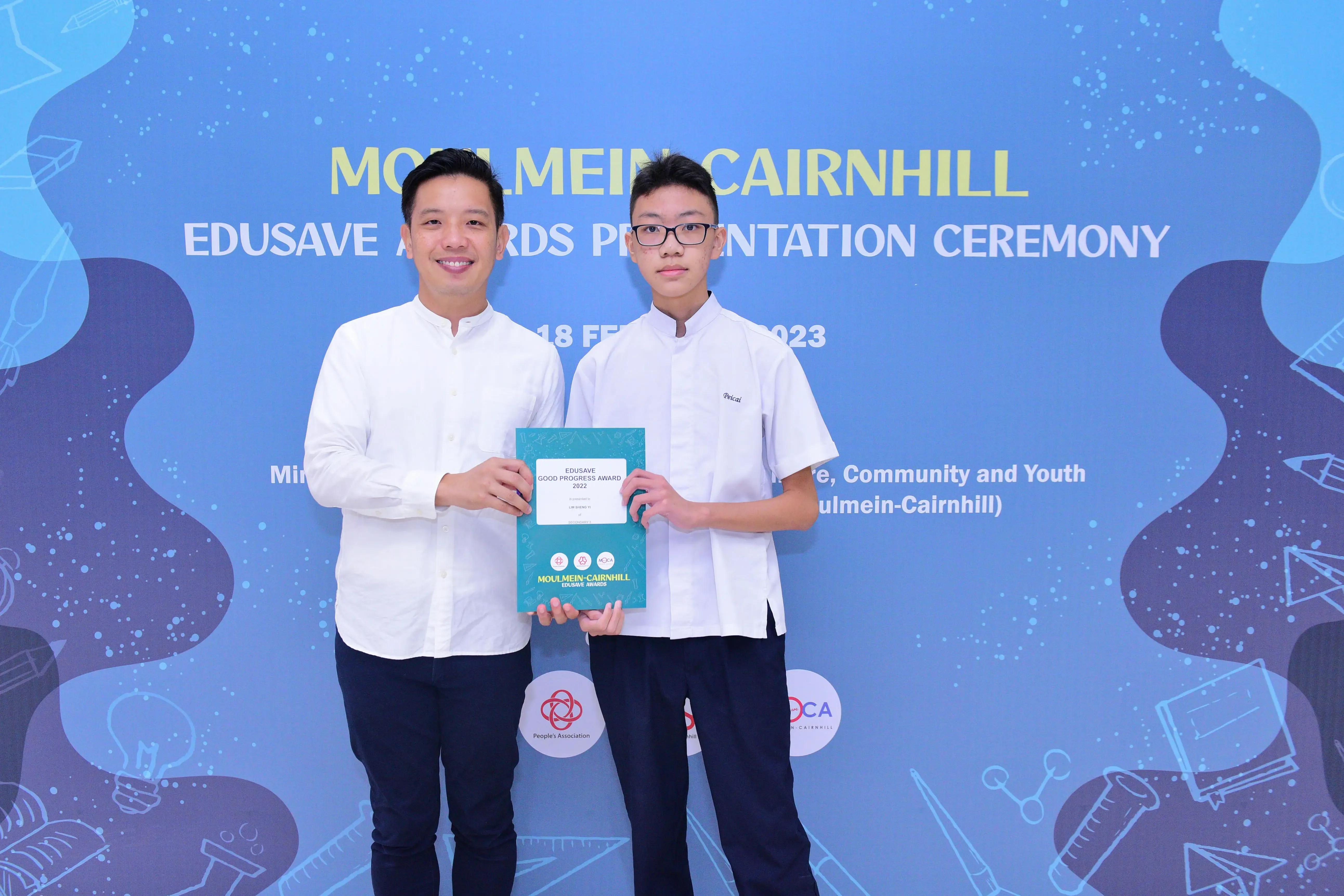 Two males hold an Edusave Good Progress Award certificate at the Moulmein-Cairnhill Edusave Awards Ceremony 2023.