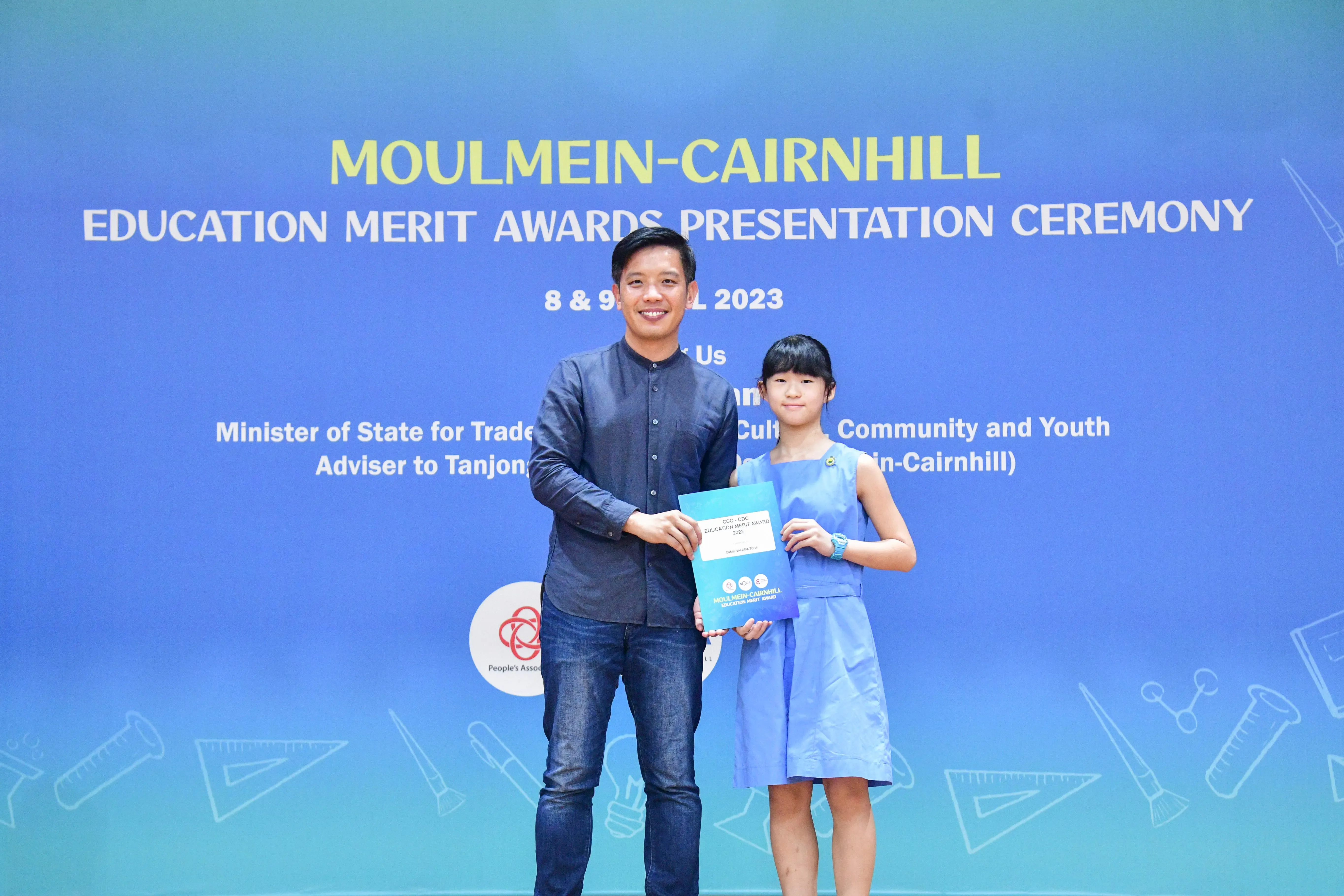 A man and a young girl hold an award certificate at the Moulmein-Cairnhill Education Merit Awards ceremony in 2023.