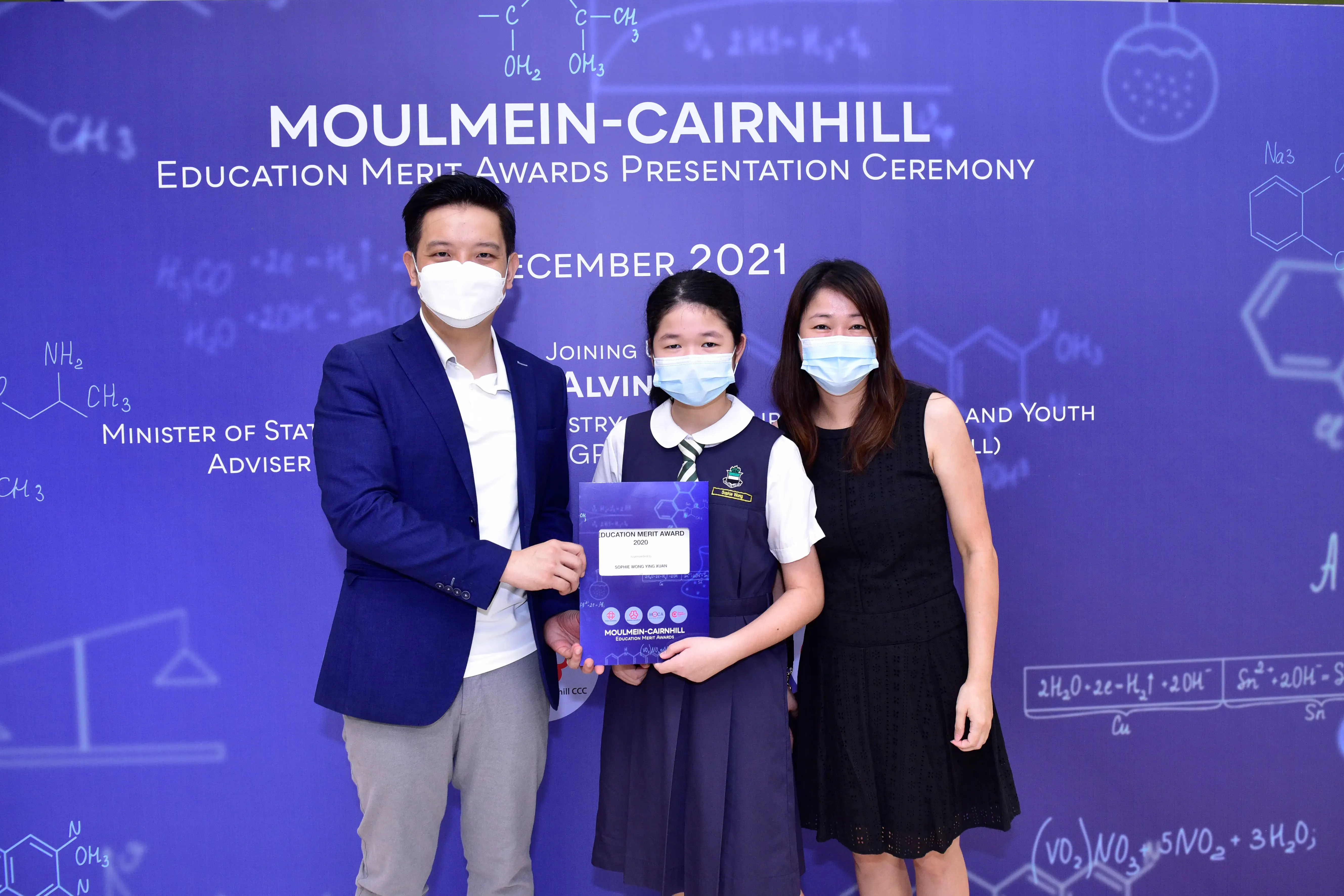 Three masked people pose at the Moulmein-Cairnhill Education Merit Awards Presentation Ceremony, December 2021.