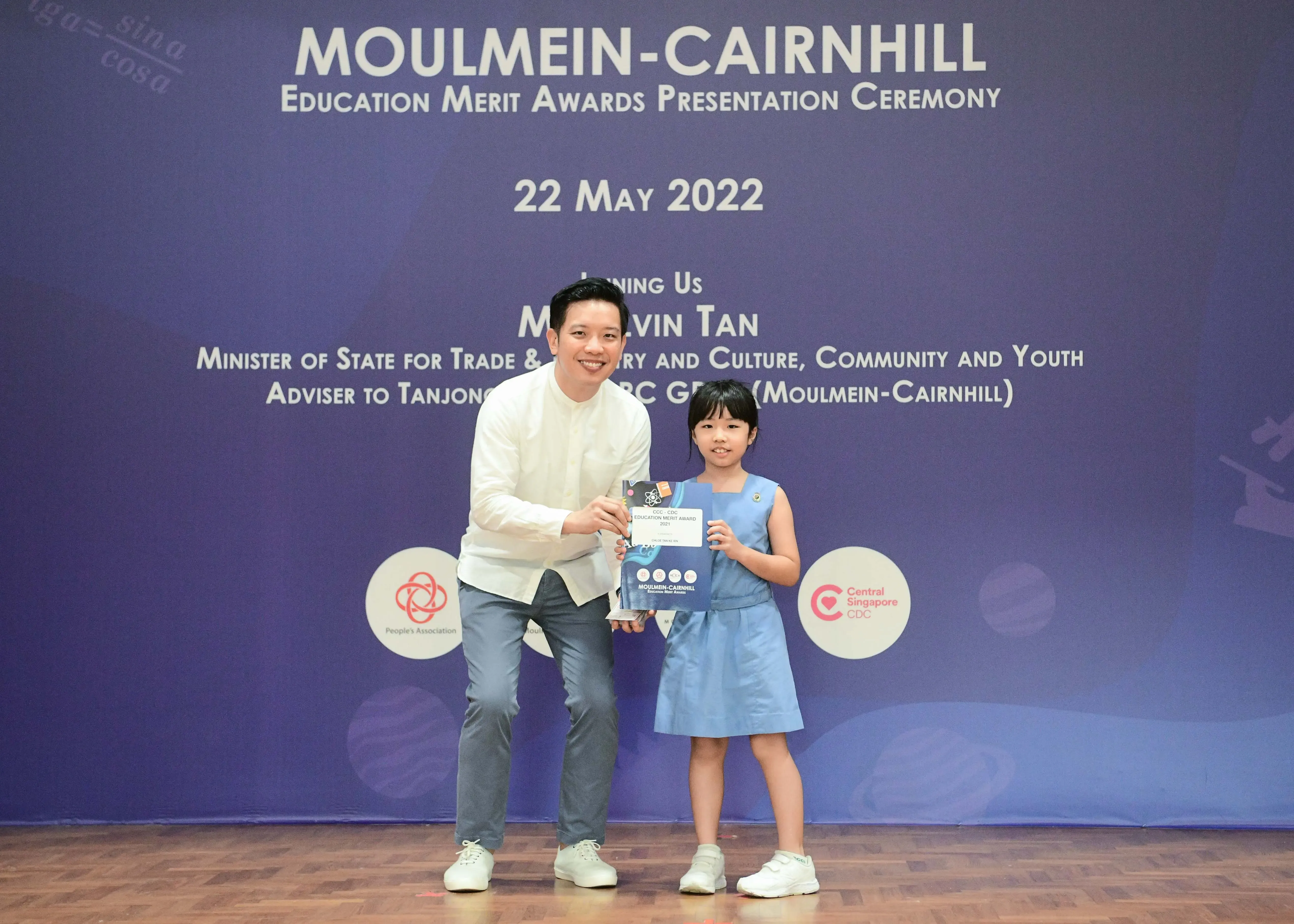 A man and a young girl hold an award certificate at the Moulmein-Cairnhill Education Merit Awards ceremony on 22 May 2022.