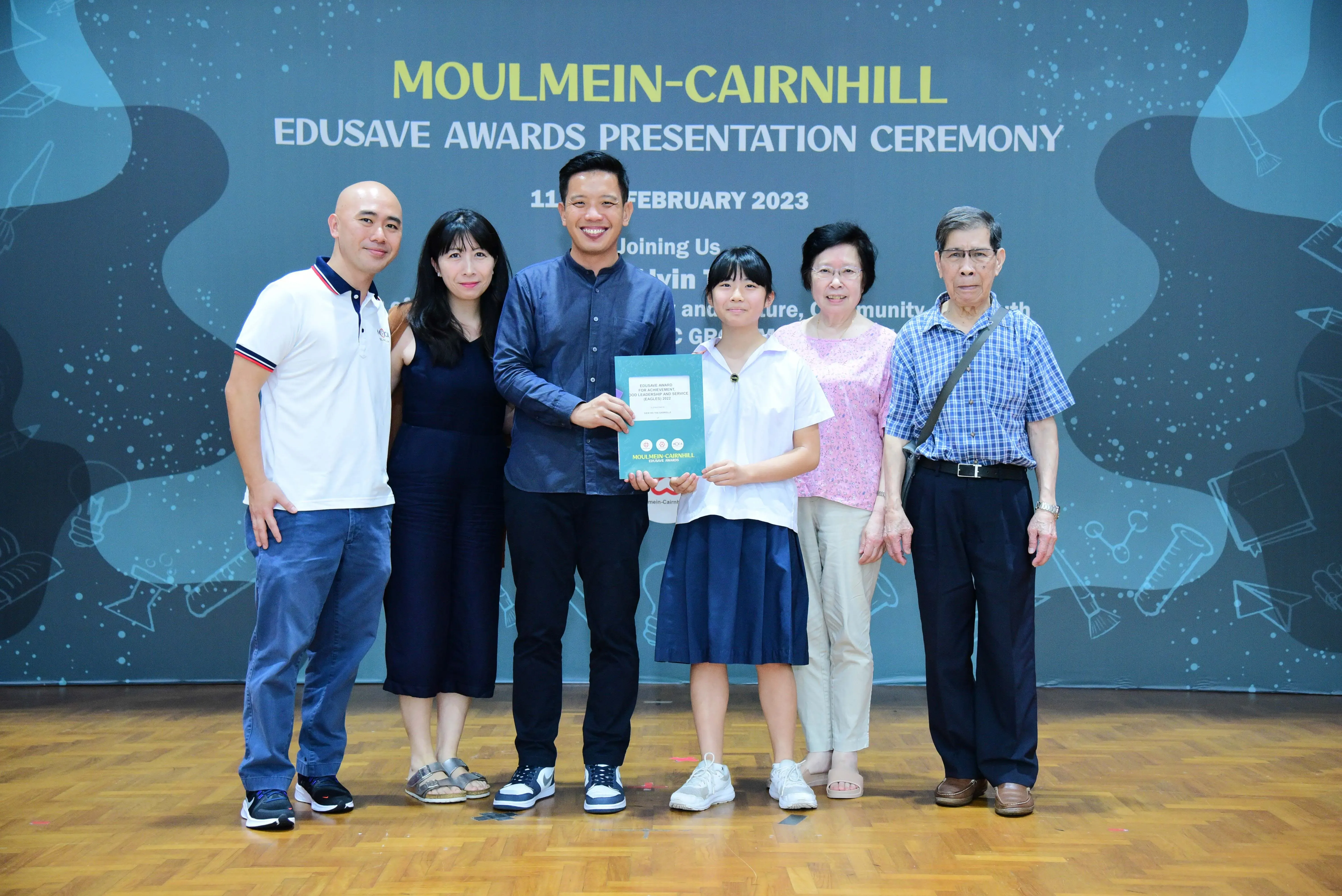 Six people pose holding a certificate at the Moulmein-Cairnhill Edusave Awards Presentation Ceremony, February 2023.