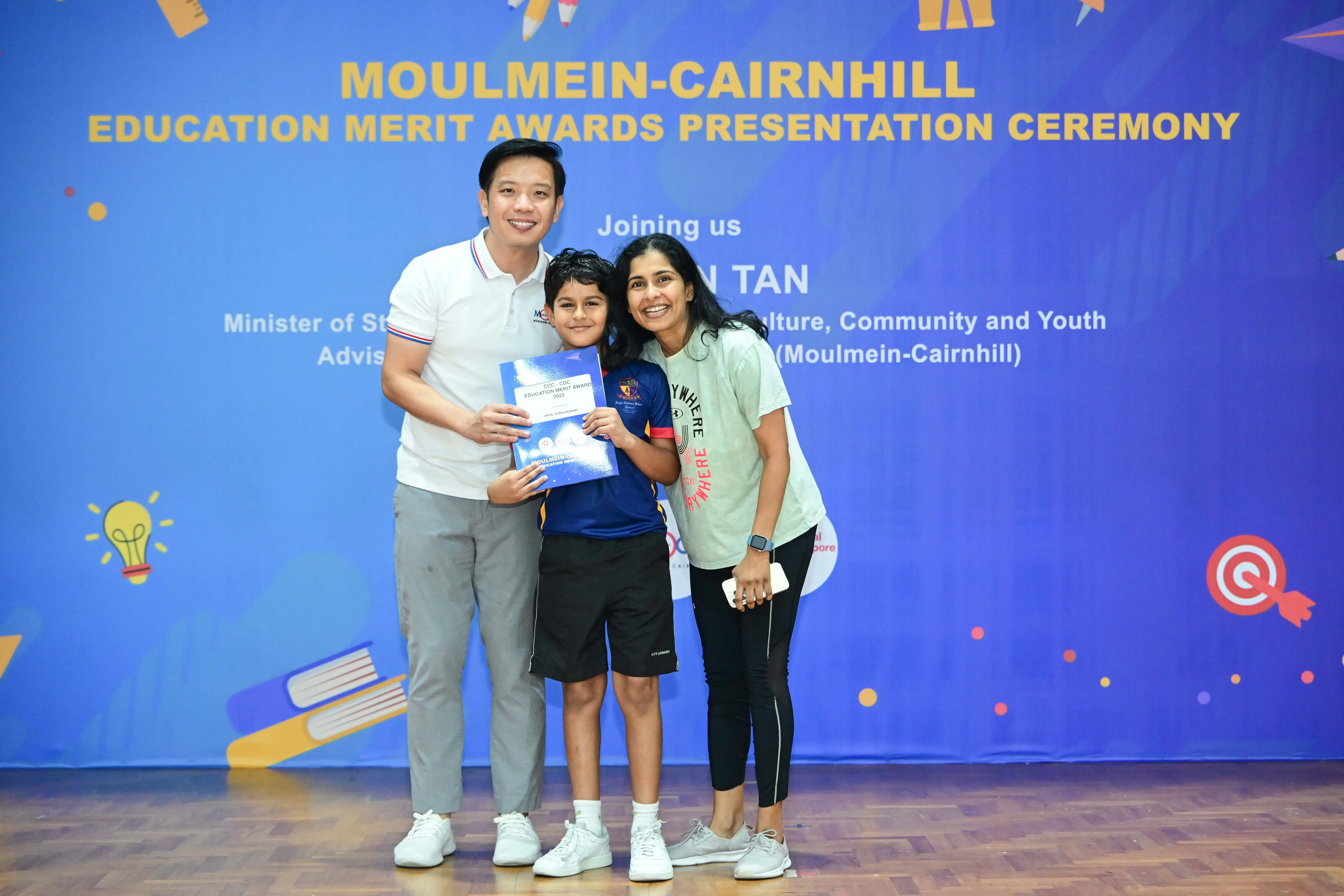 Three people pose with a certificate at the Moulmein-Cairnhill Education Merit Awards Presentation Ceremony.