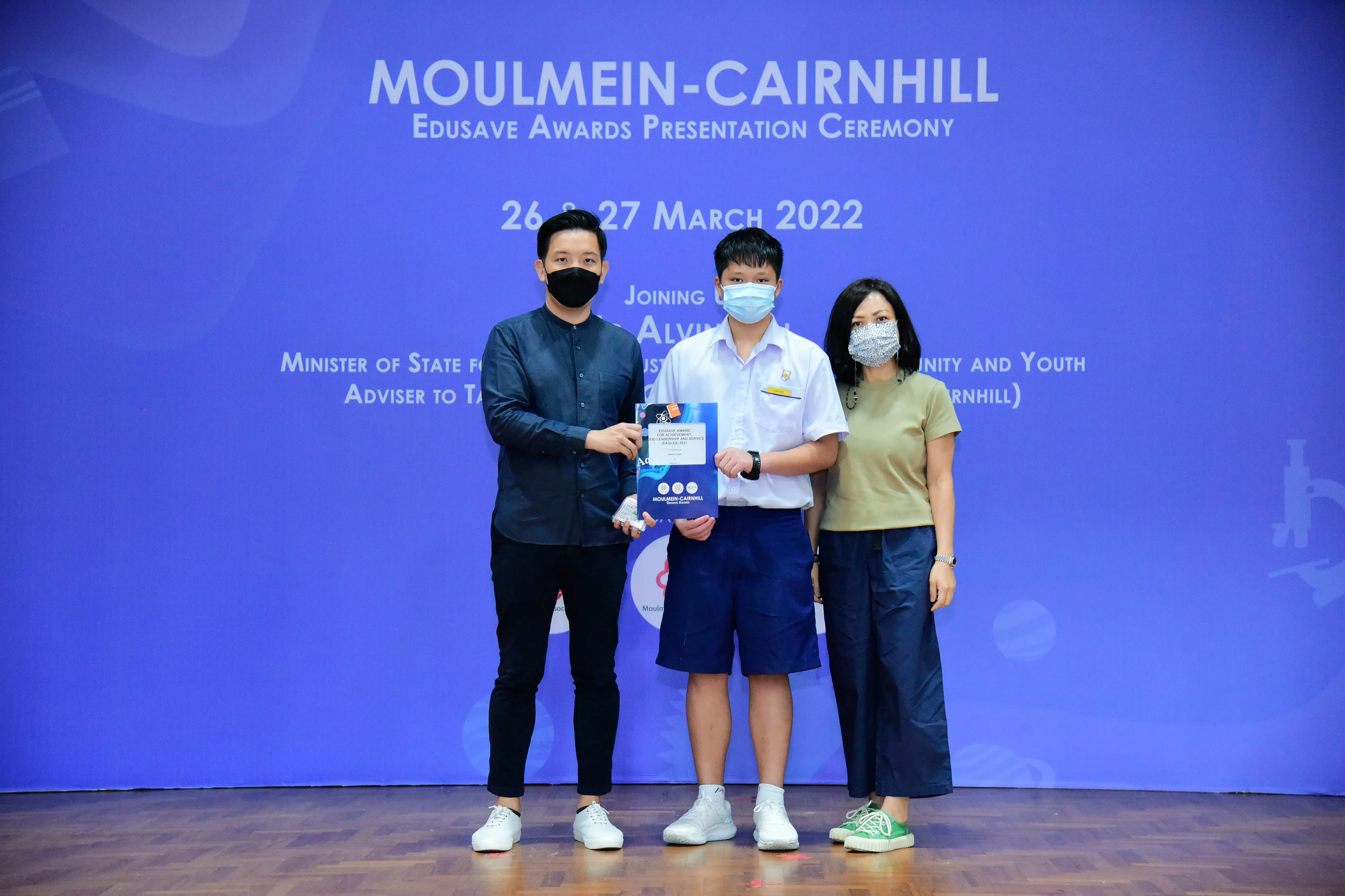 Three masked people pose at the Moulmein-Cairnhill Edusave Awards Ceremony on 26-27 March 2022.
