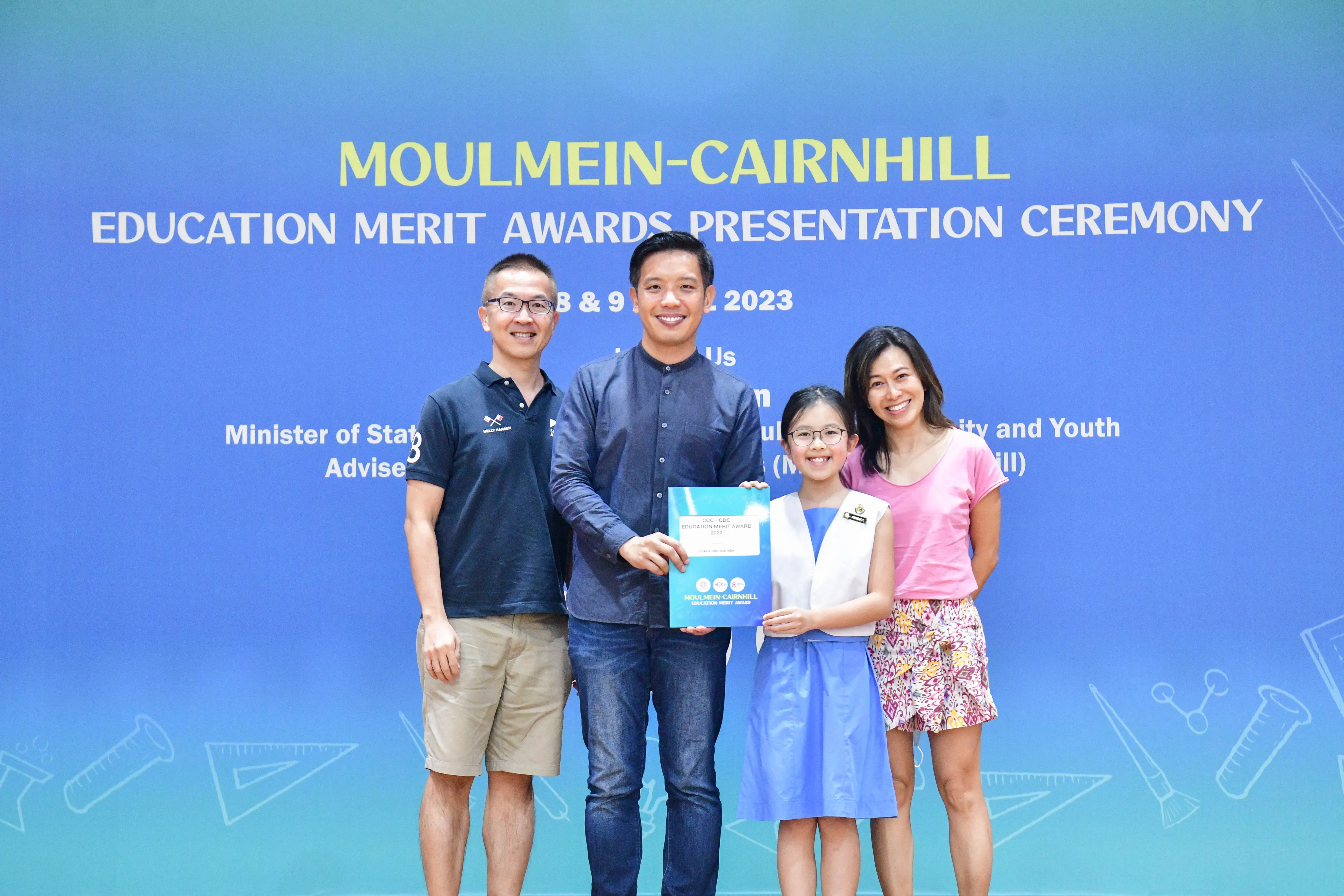 Four people pose at the Moulmein-Cairnhill Education Merit Awards Presentation Ceremony 2023, a girl holding an award.