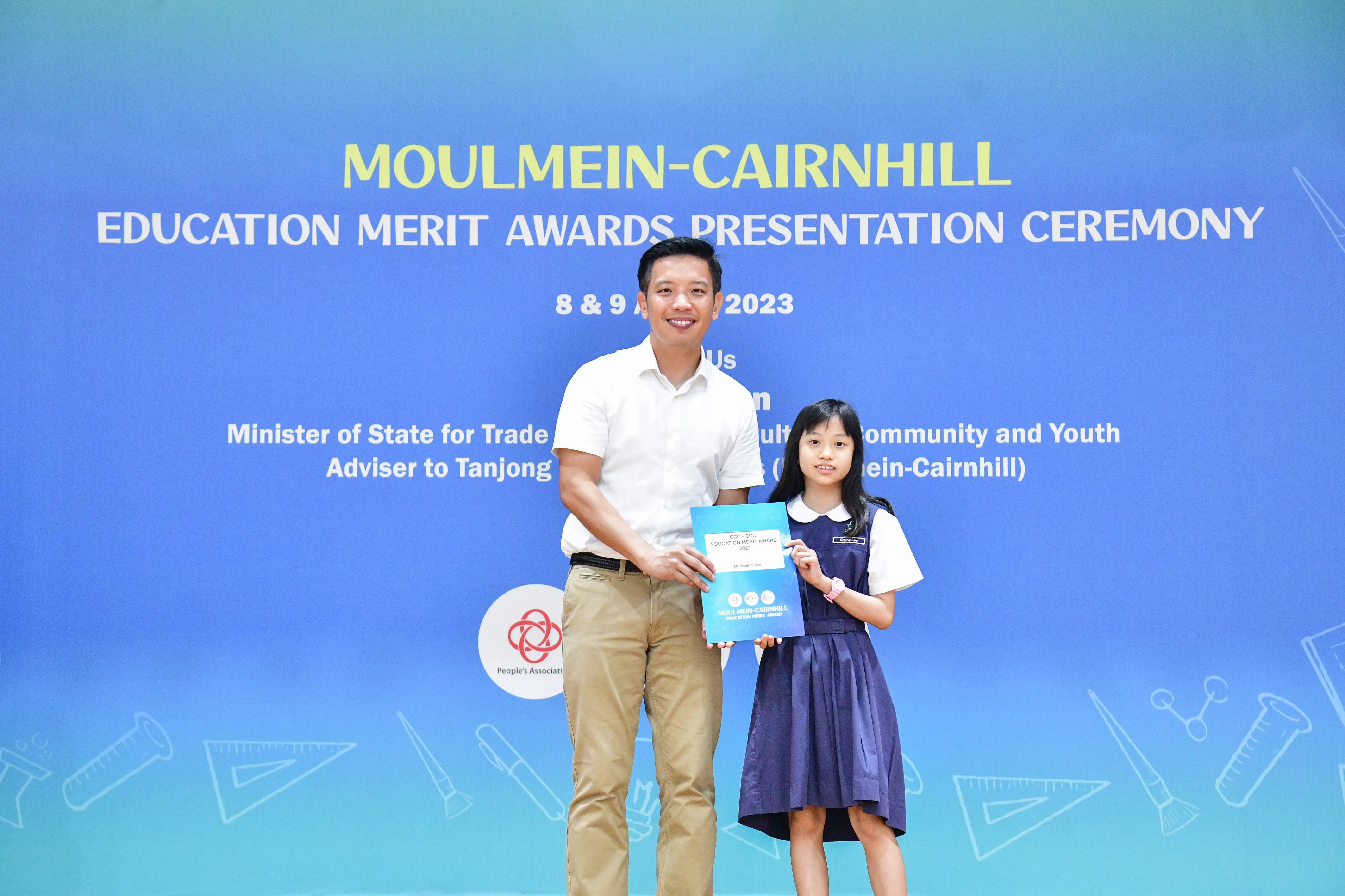 A man and a young girl hold a certificate together at the Moulmein-Cairnhill Education Merit Awards Ceremony 2023.