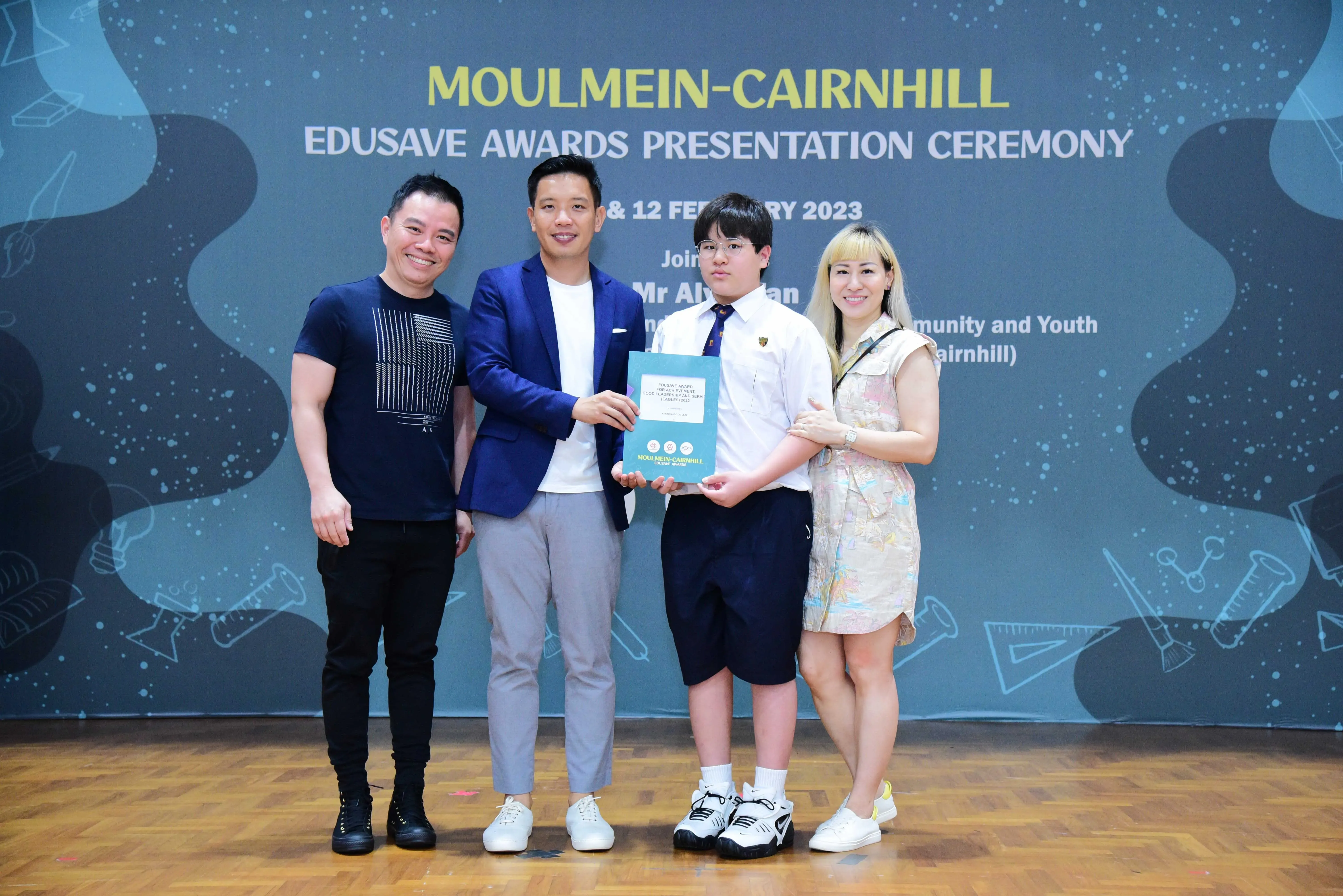 Four people pose holding a certificate at the Moulmein-Cairnhill Edusave Awards Presentation Ceremony, February 2023.