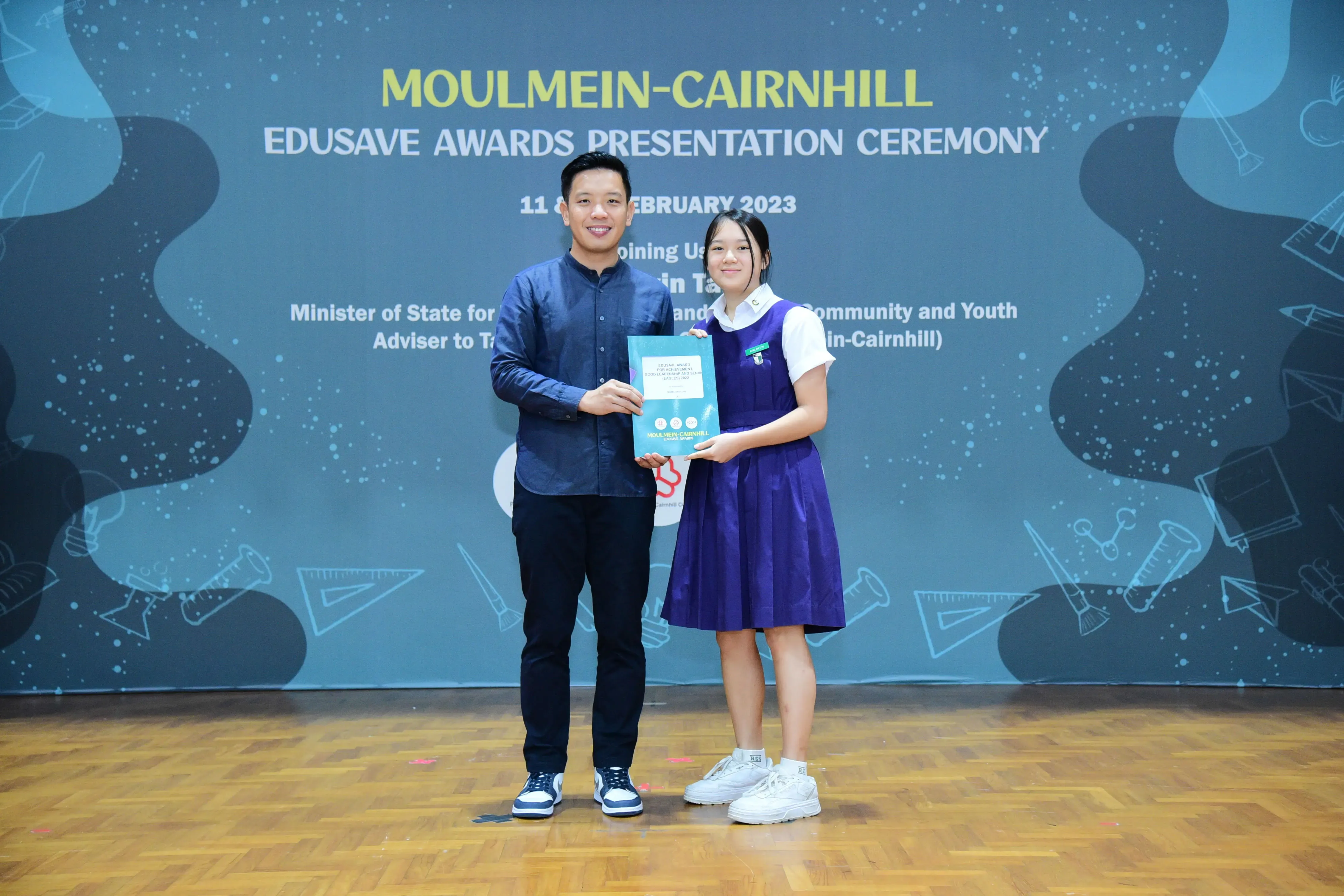 Man and girl in school uniform hold a certificate at Moulmein-Cairnhill Edusave Awards Presentation Ceremony 2023.