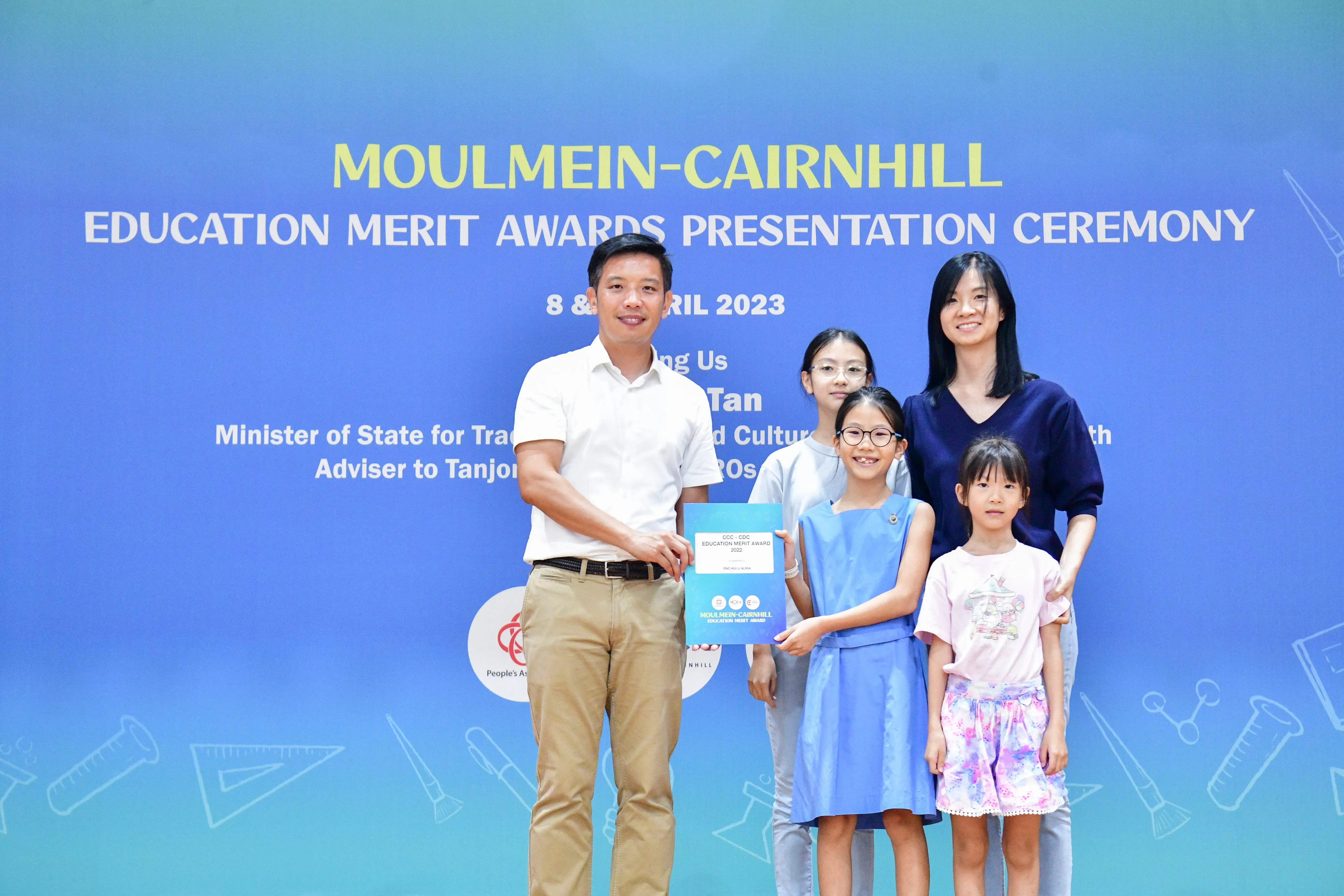 A man and woman pose with three young girls holding an award at the Moulmein-Cairnhill Education Merit Awards 2023.