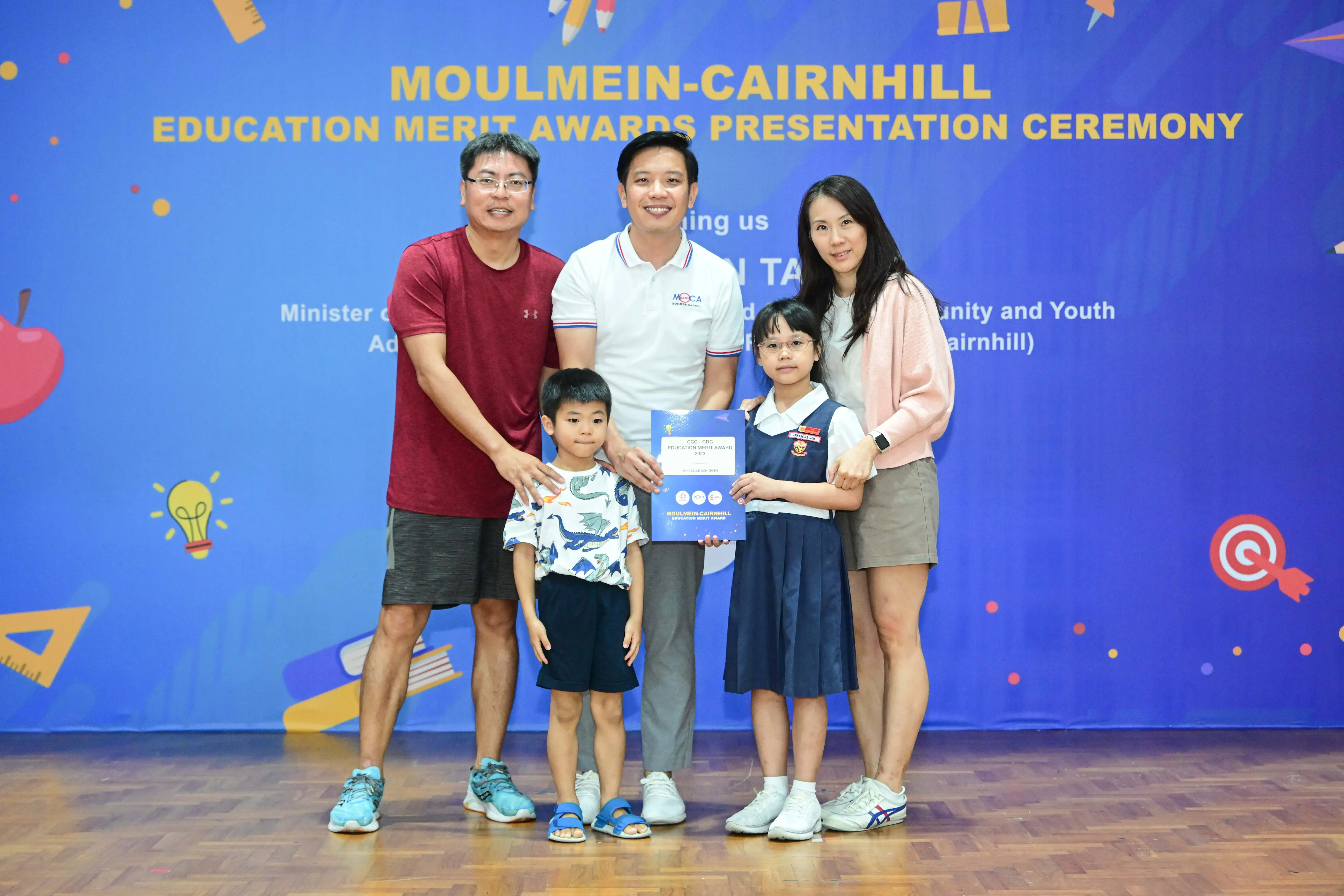 Family of five posing at Moulmein-Cairnhill Education Merit Awards ceremony, girl holding award certificate.