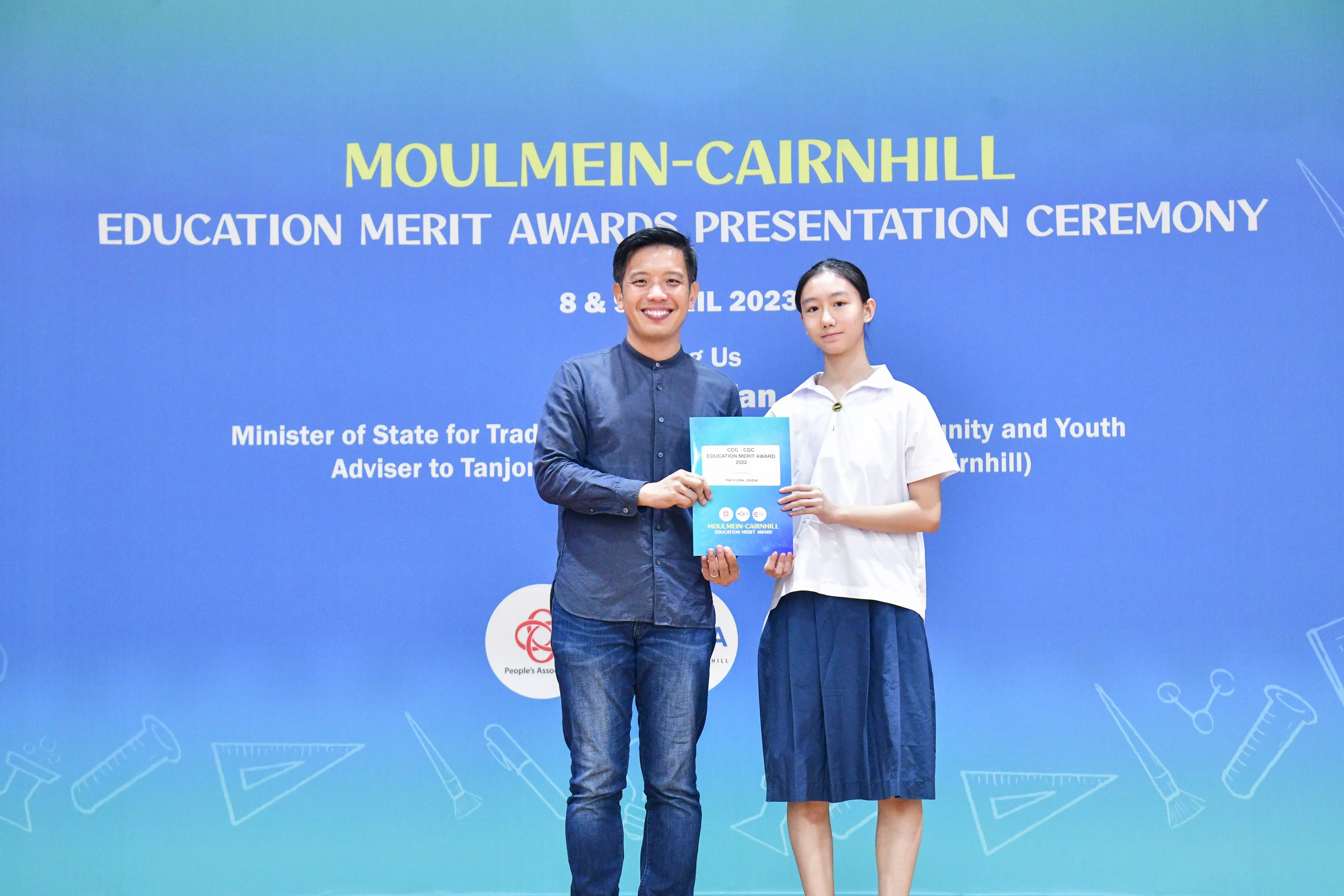 A man and a young girl hold an award certificate together at the Moulmein-Cairnhill Education Merit Awards 2023.