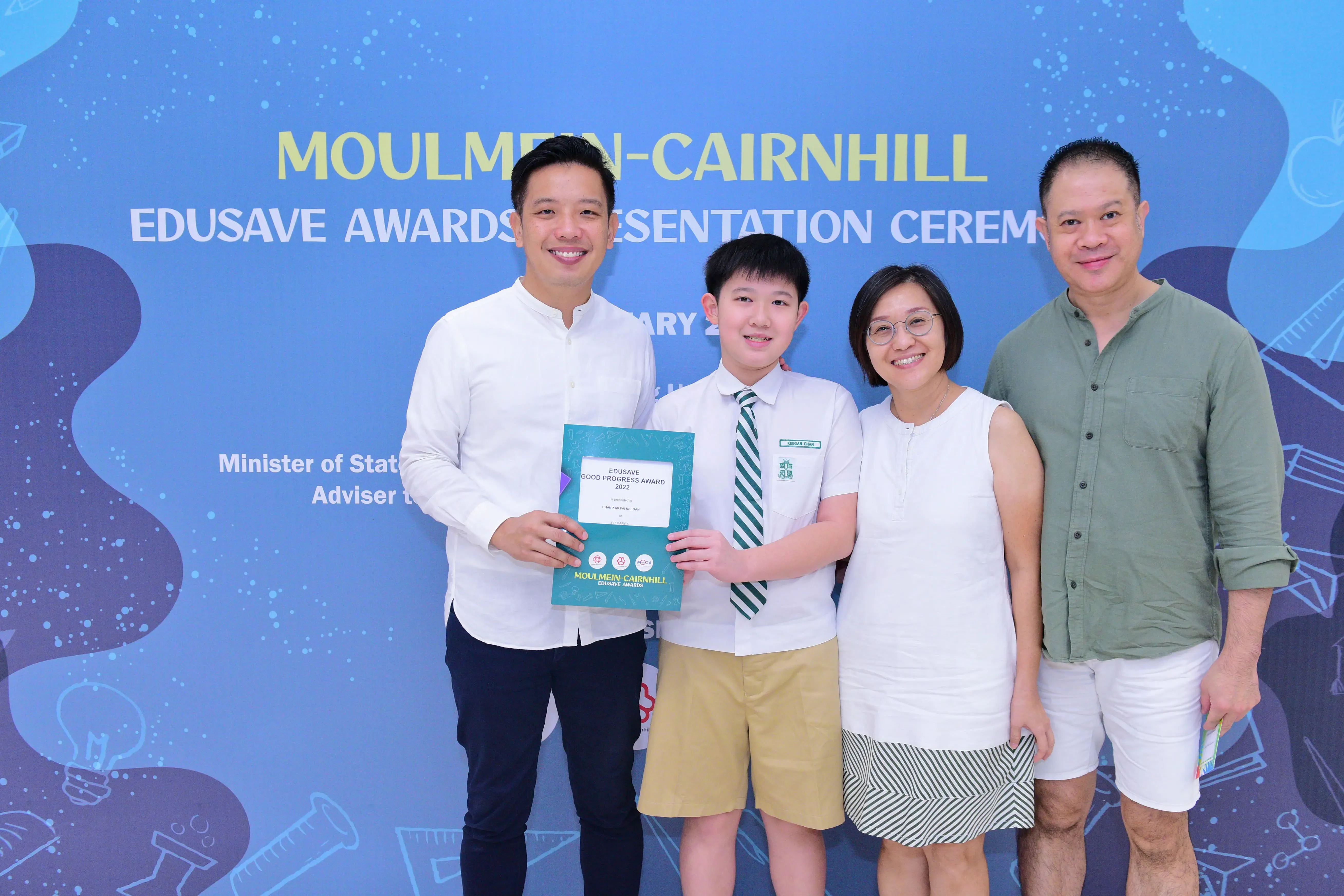 Four people pose with an Edusave Good Progress Award 2022 certificate at the Moulmein-Cairnhill Awards Ceremony.