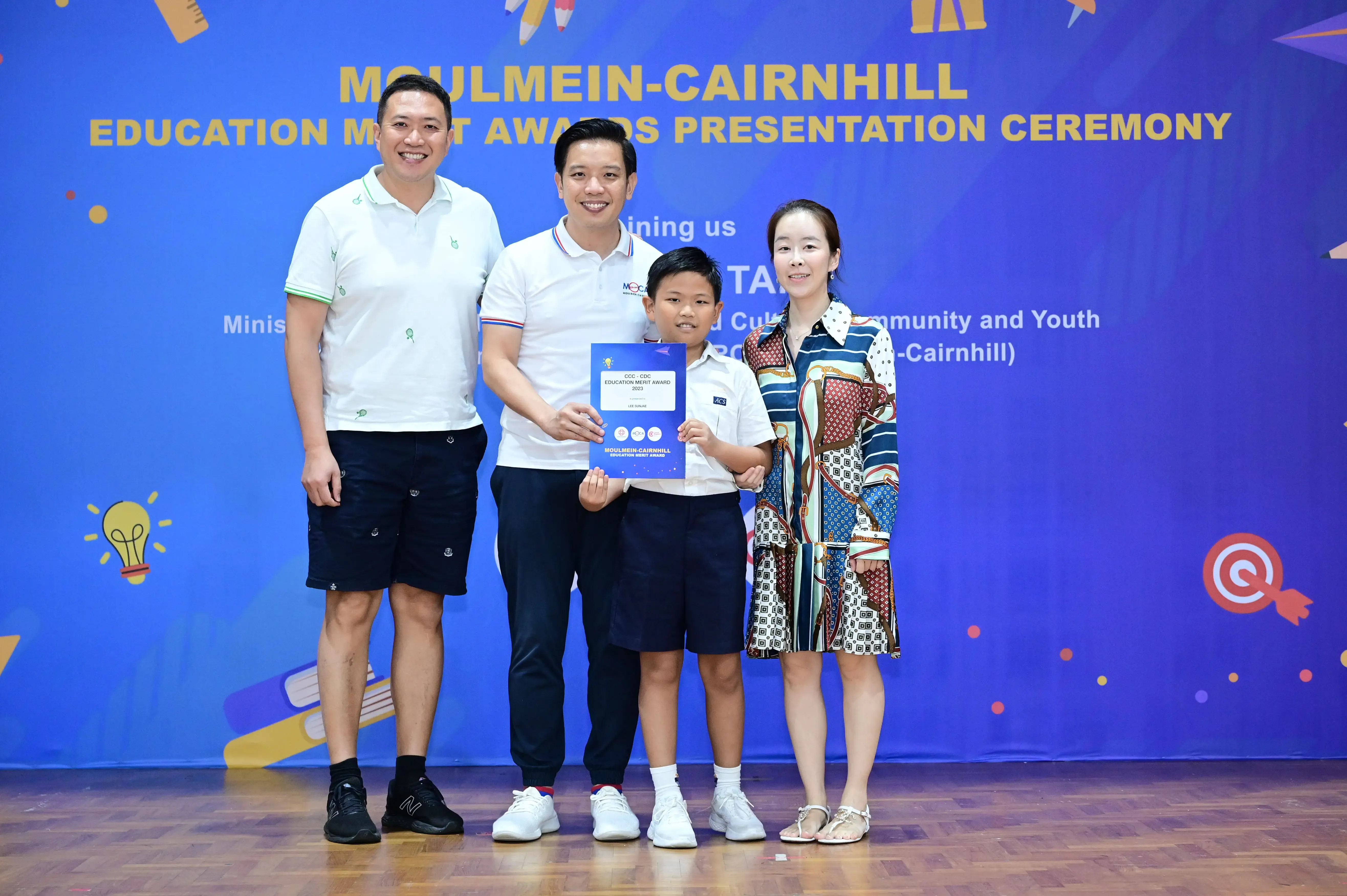 Three adults and a boy pose with a certificate at the Moulmein-Cairnhill Education Merit Awards Presentation Ceremony.