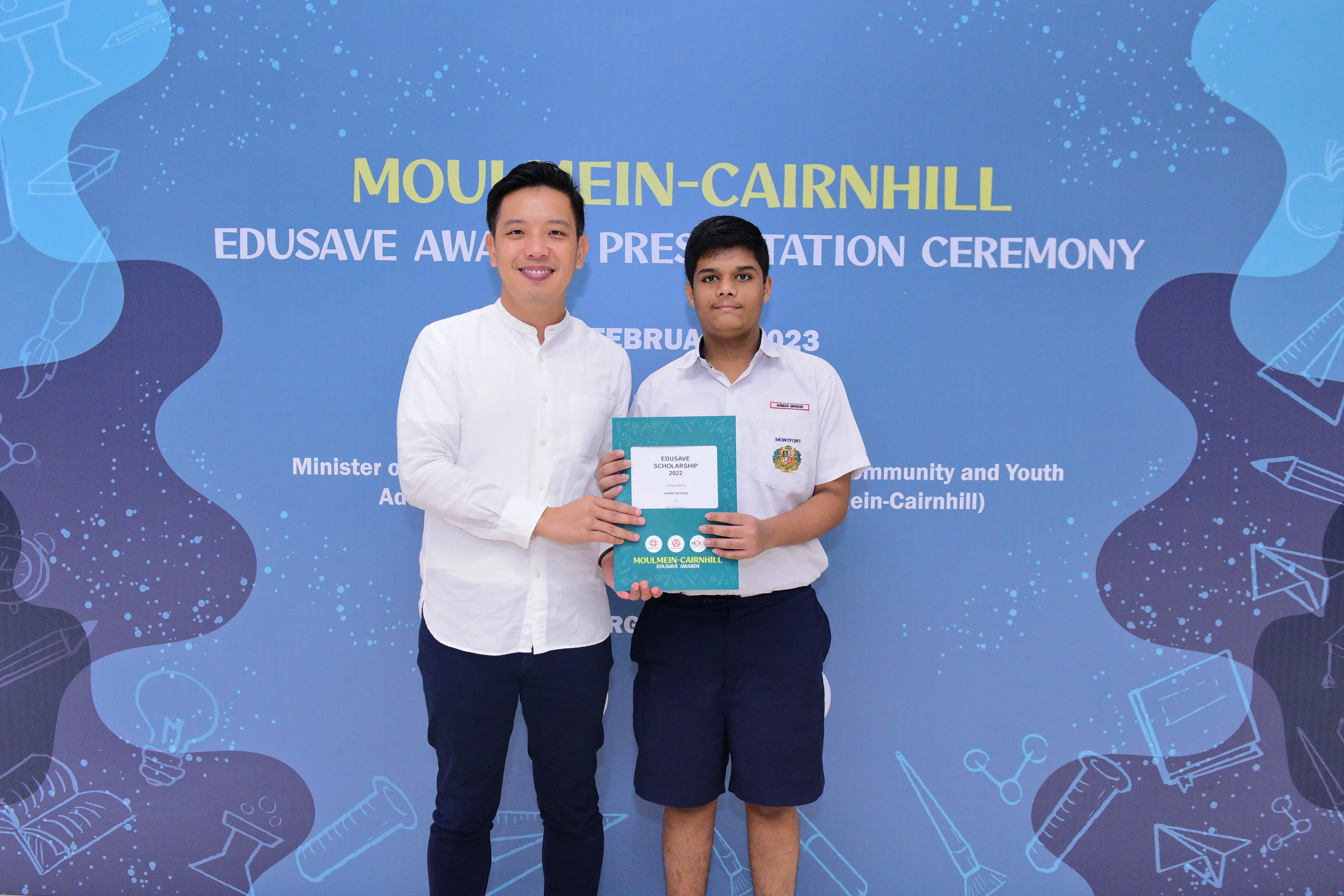 Two people hold an Edusave Scholarship certificate at the Moulmein-Cairnhill Edusave Awards Presentation Ceremony 2023.