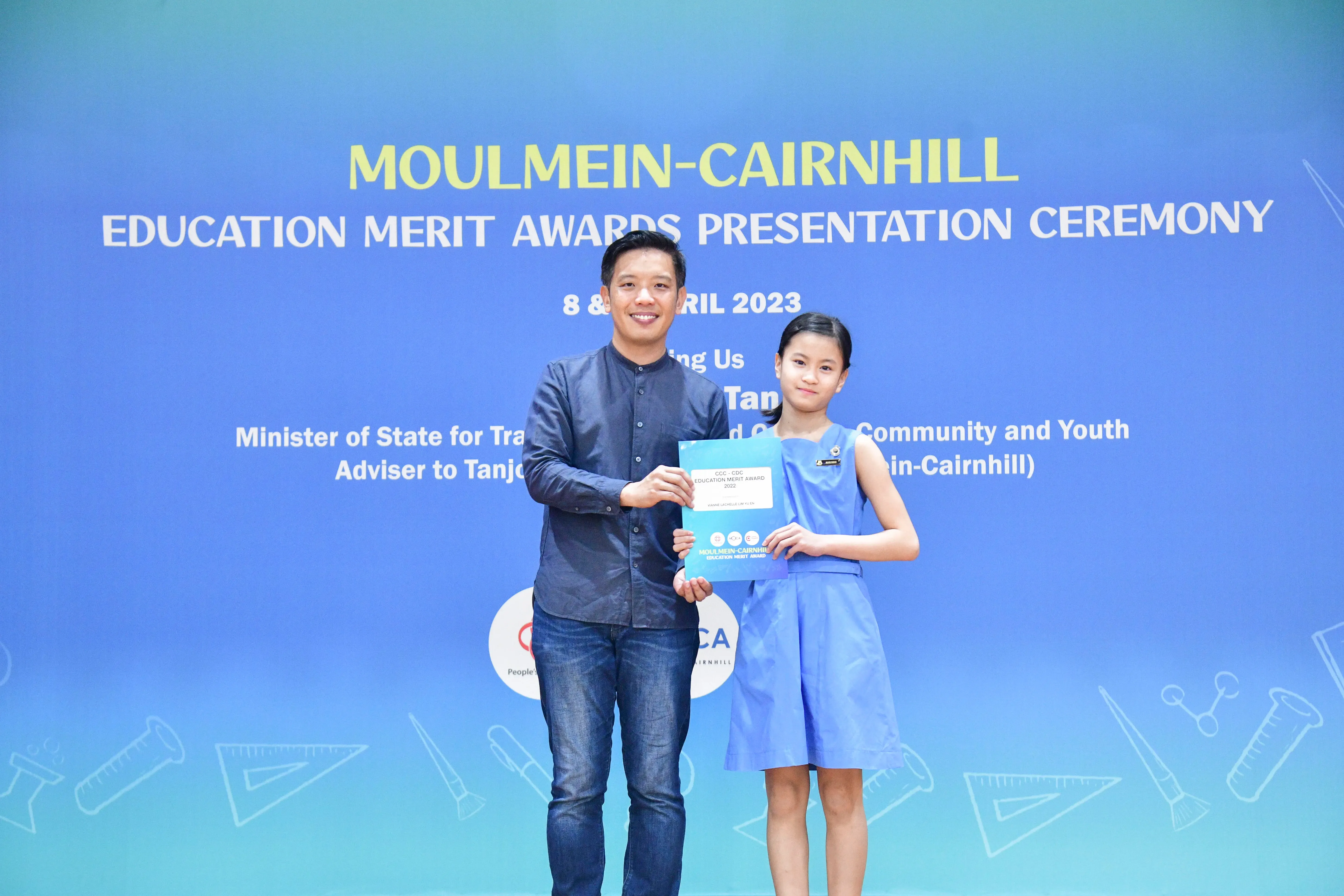 A man and a young girl hold a certificate at the Moulmein-Cairnhill Education Merit Awards Ceremony, April 2023.