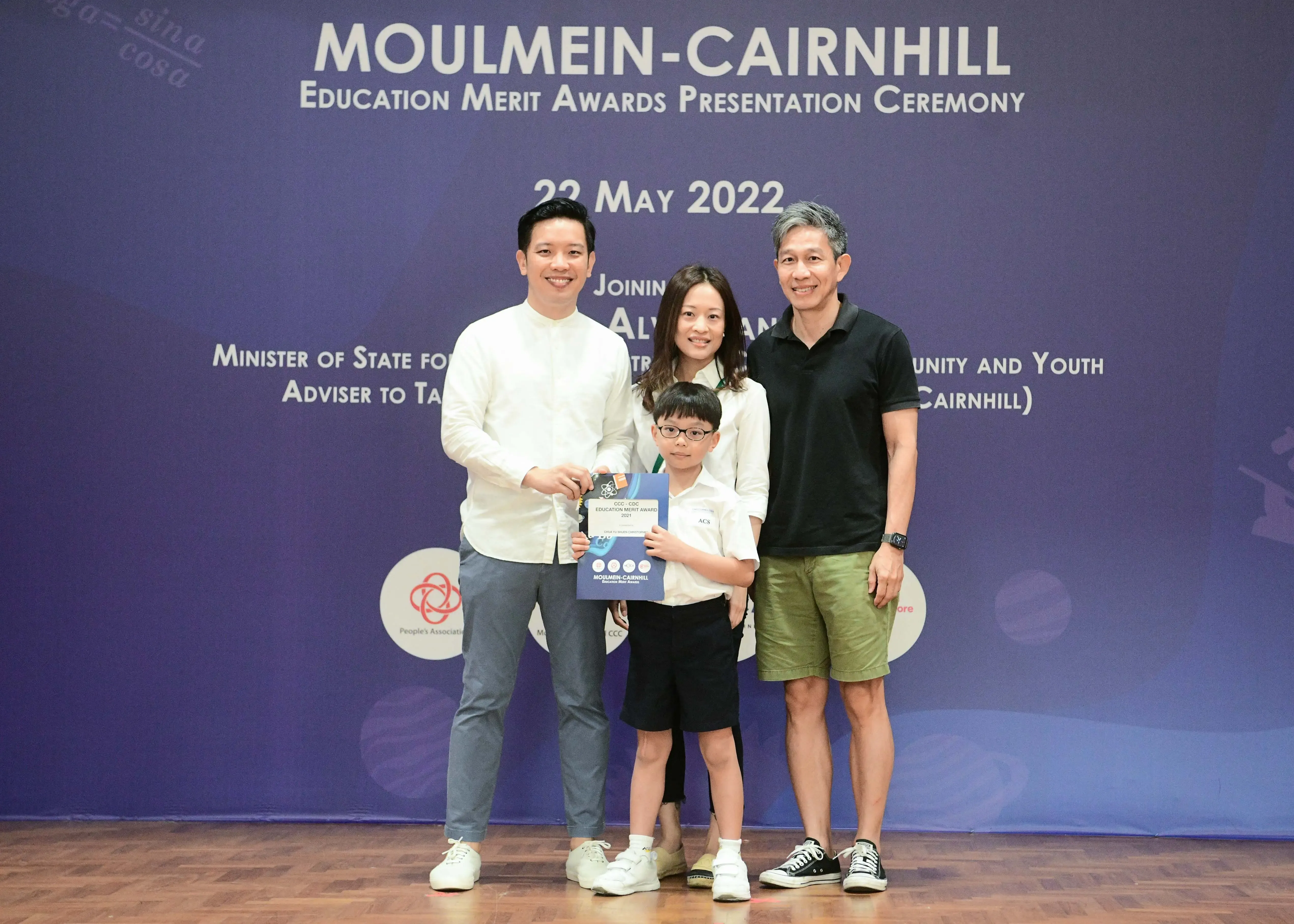 Three adults and a young boy holding an award certificate pose at the Moulmein-Cairnhill Education Merit Awards ceremony on 22 May 2022.