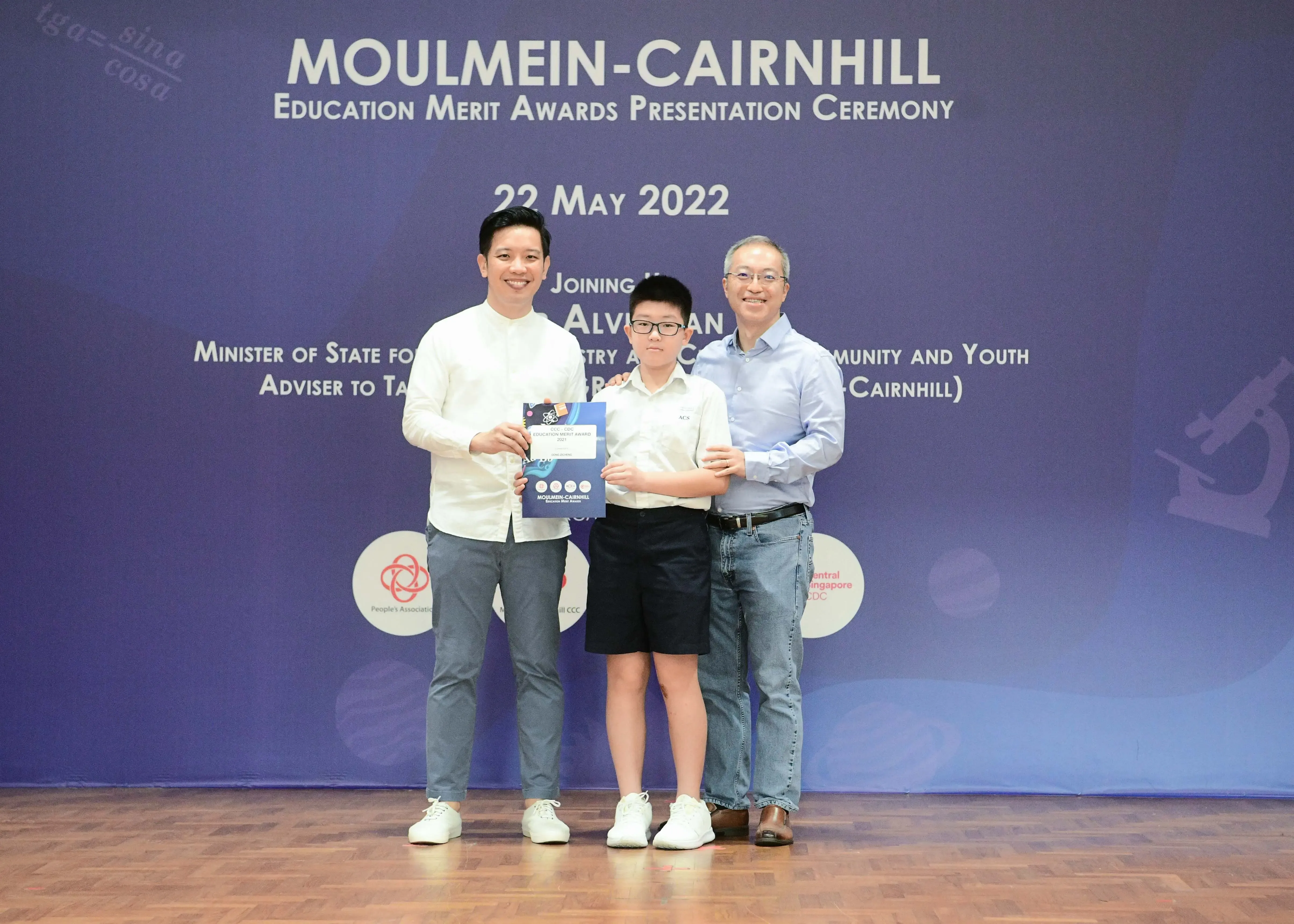 Three people pose with an award certificate at the Moulmein-Cairnhill Education Merit Awards Ceremony on 22 May 2022.