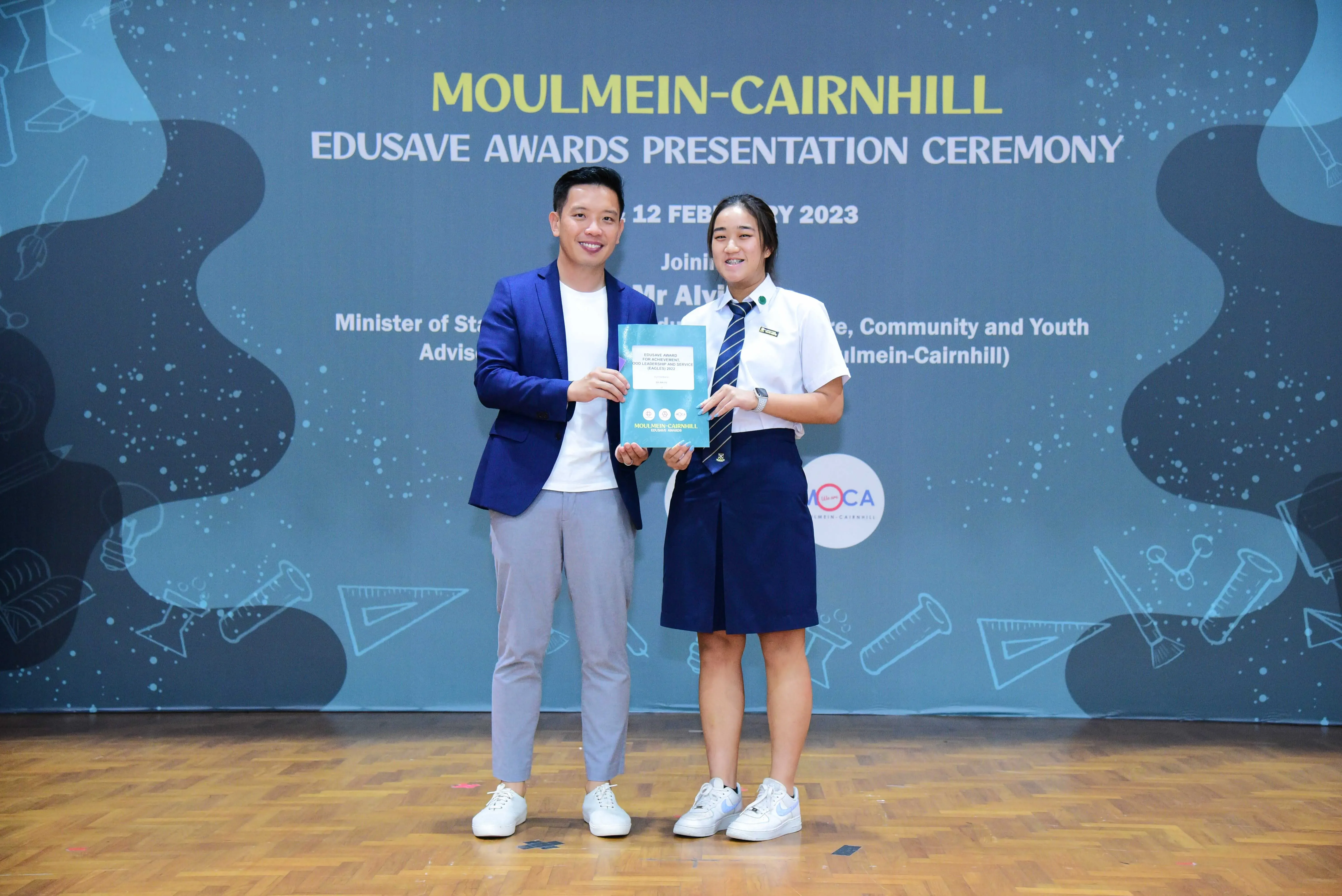 Two people hold an award booklet at the Moulmein-Cairnhill Edusave Awards Presentation Ceremony on 12 February 2023.