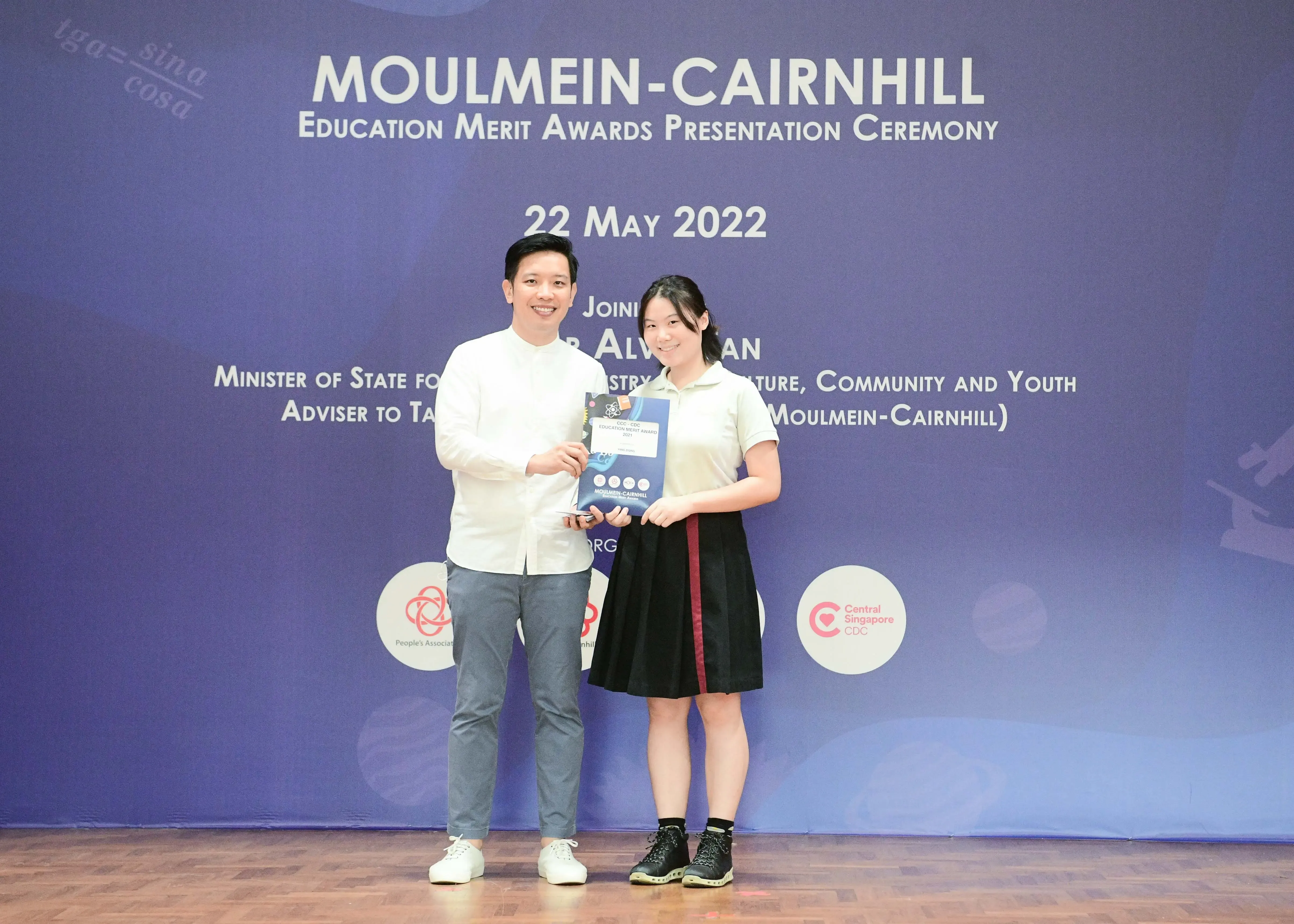 Two people hold an award booklet at the Moulmein-Cairnhill Education Merit Awards Presentation Ceremony on 22 May 2022.