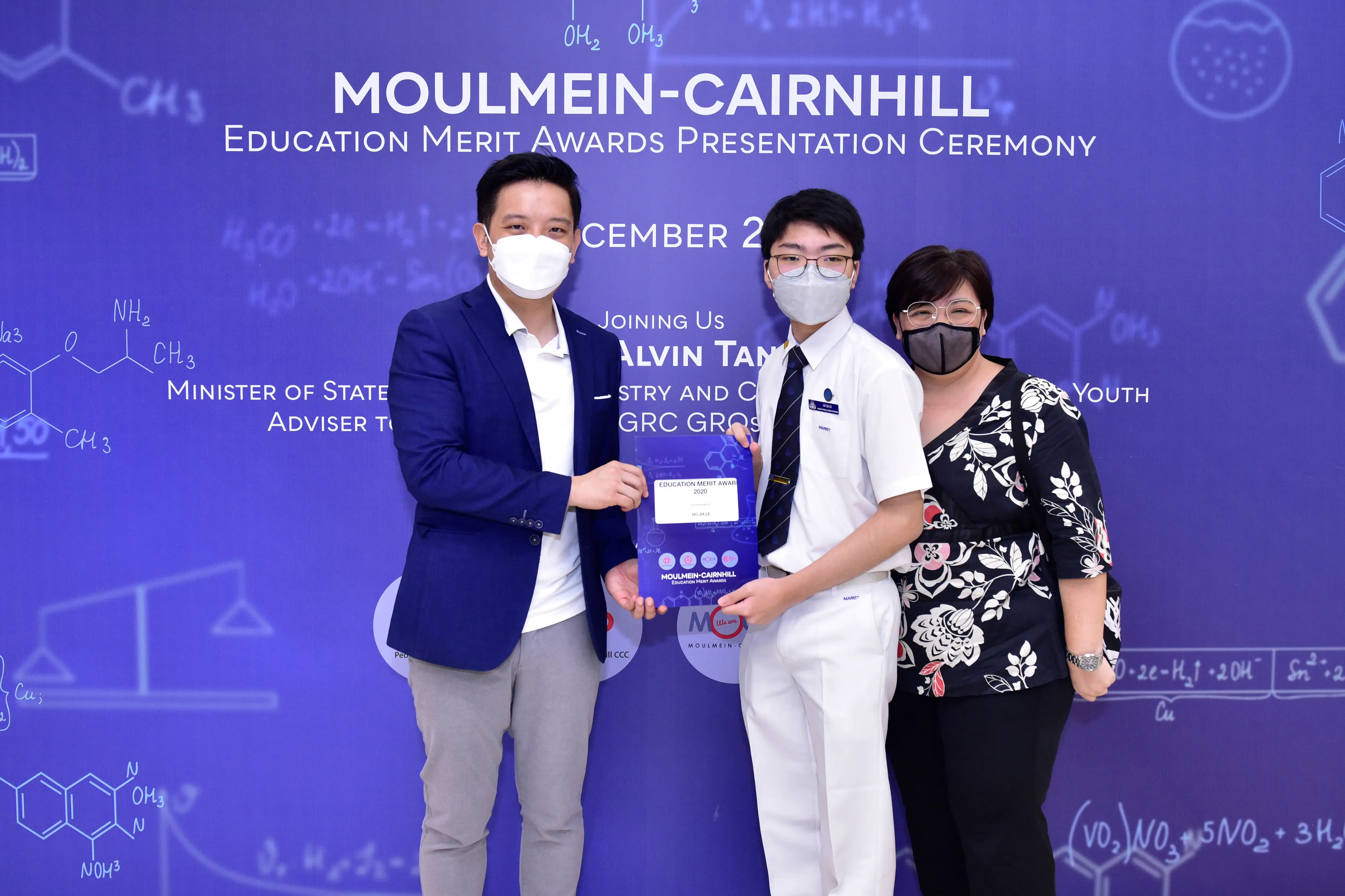 Three masked people pose with an award at the Moulmein-Cairnhill Education Merit Awards Presentation Ceremony.