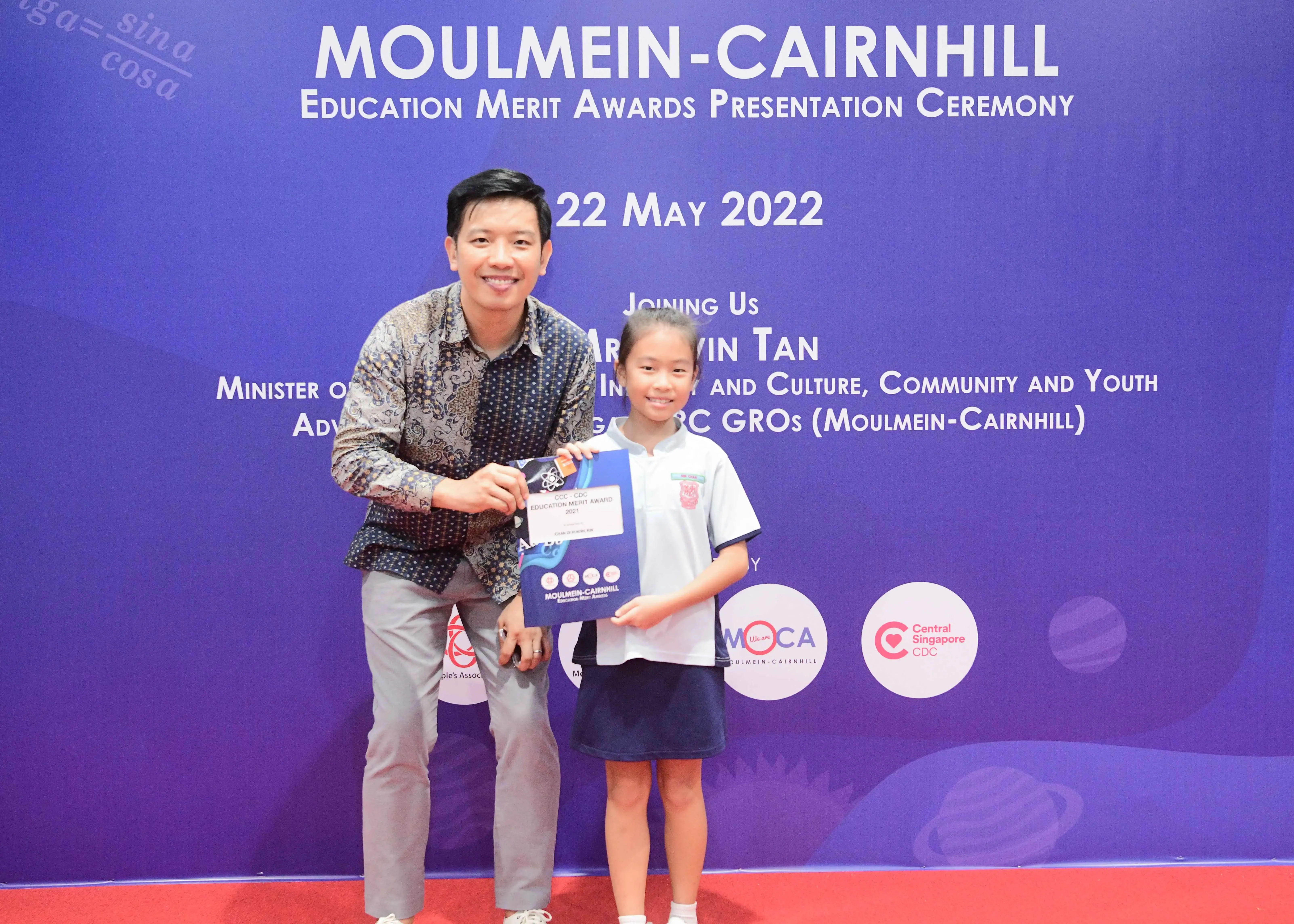 A man and a young girl hold an award certificate at the Moulmein-Cairnhill Education Merit Awards on 22 May 2022.