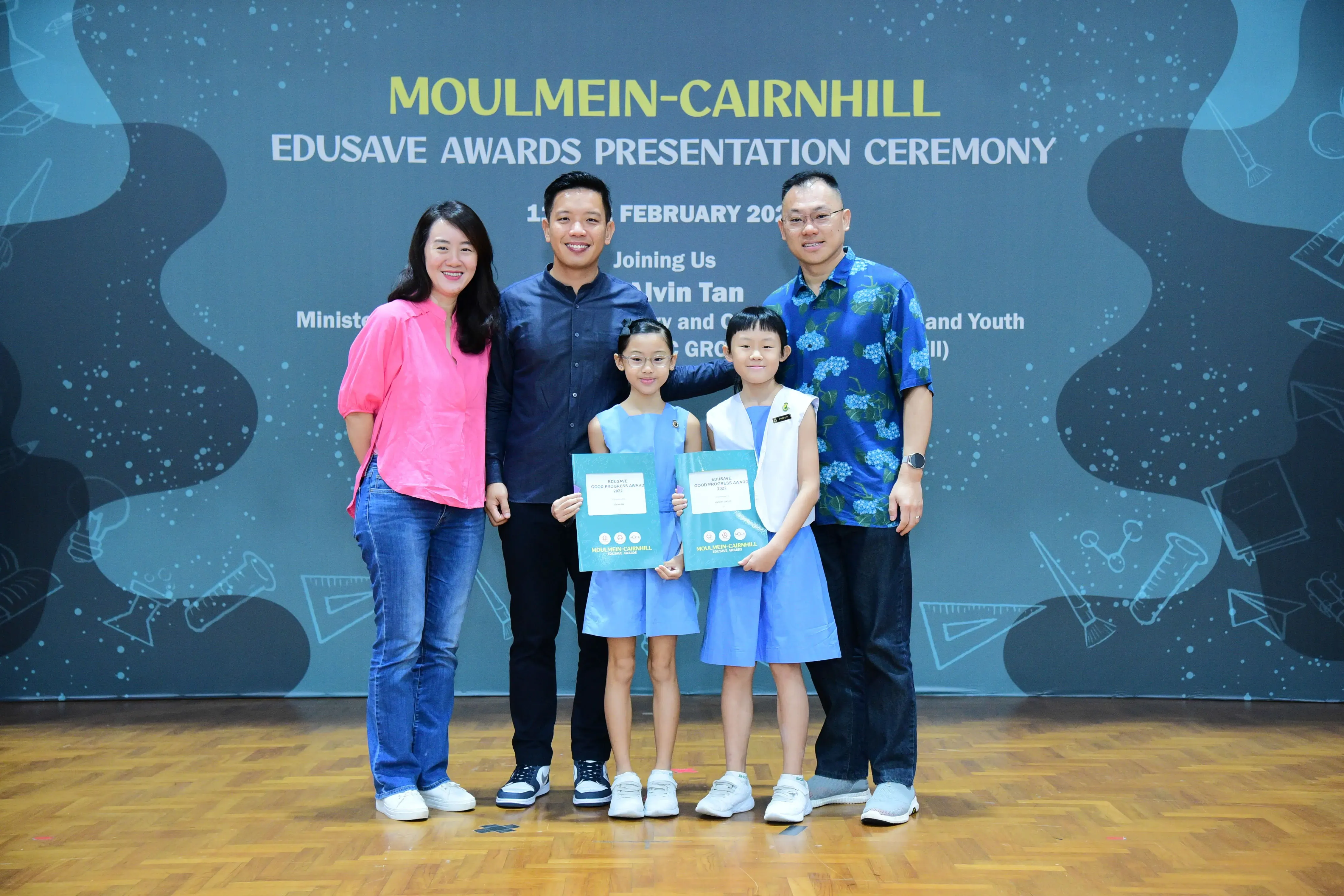 Two adults and two young girls holding certificates pose at the Moulmein-Cairnhill Edusave Awards Presentation Ceremony.