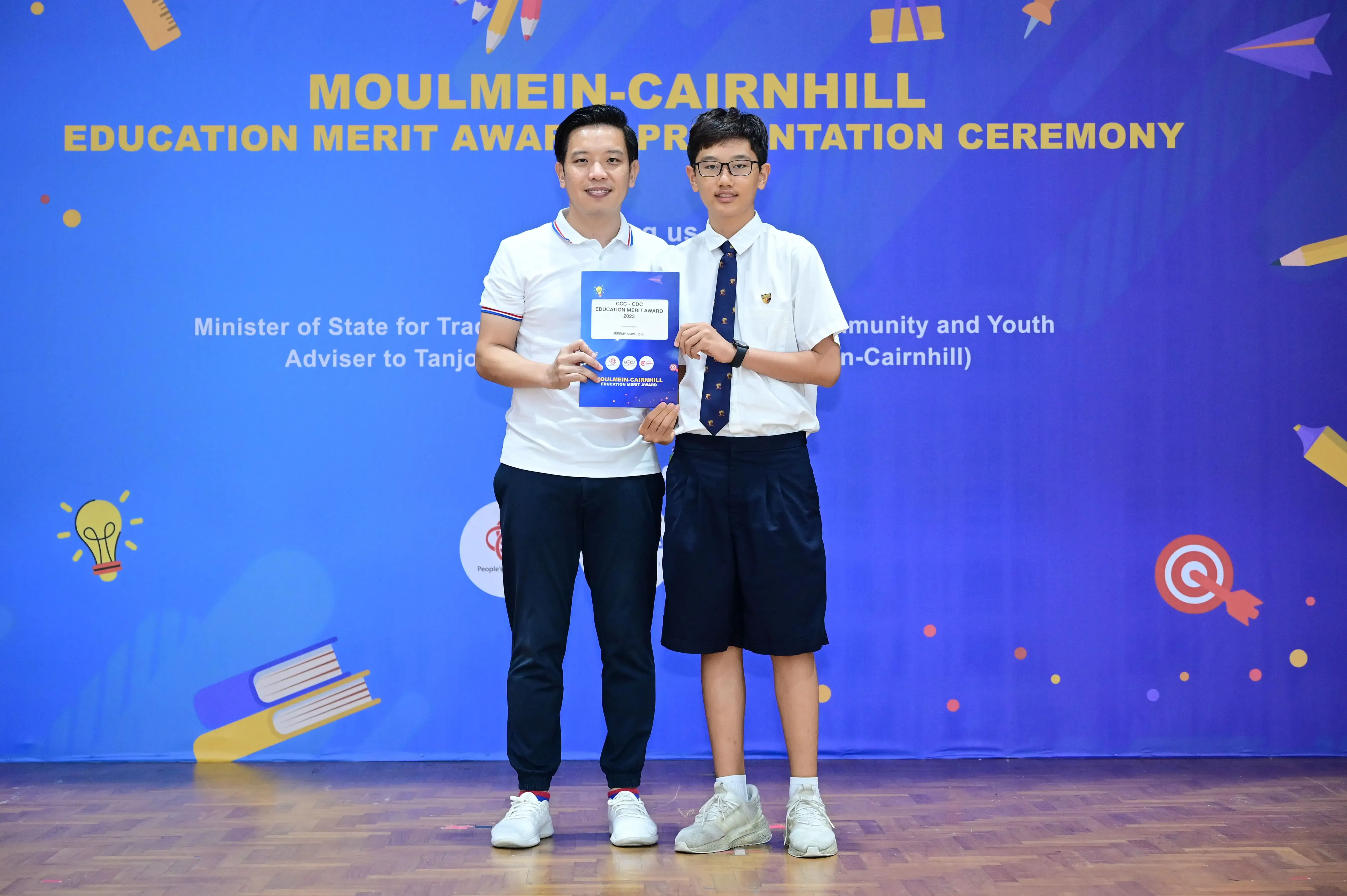 Two men hold an award certificate at the Moulmein-Cairnhill Education Merit Award Presentation Ceremony.