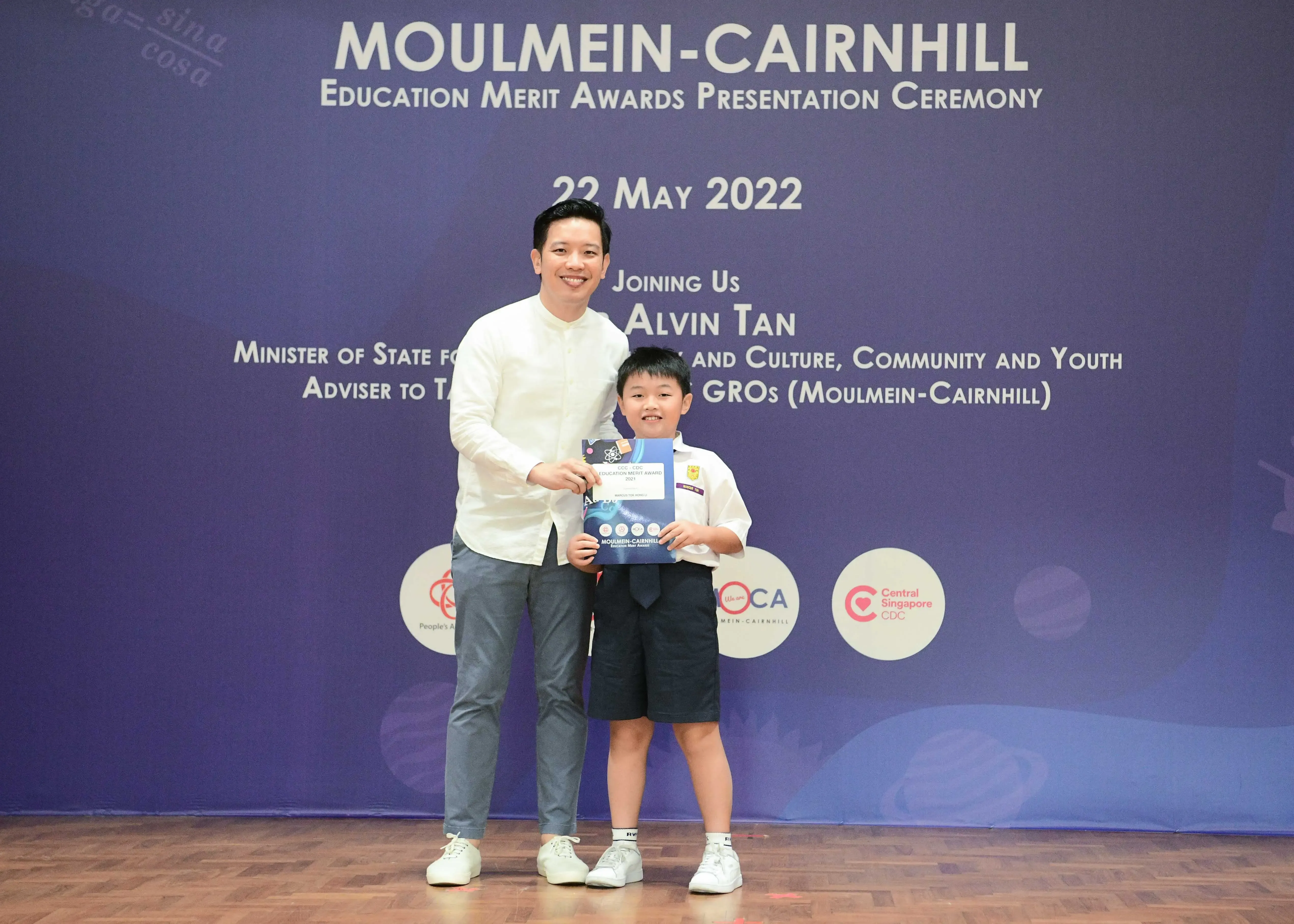 A man and a young boy pose together holding an award at the Moulmein-Cairnhill Education Merit Awards ceremony on 22 May 2022.