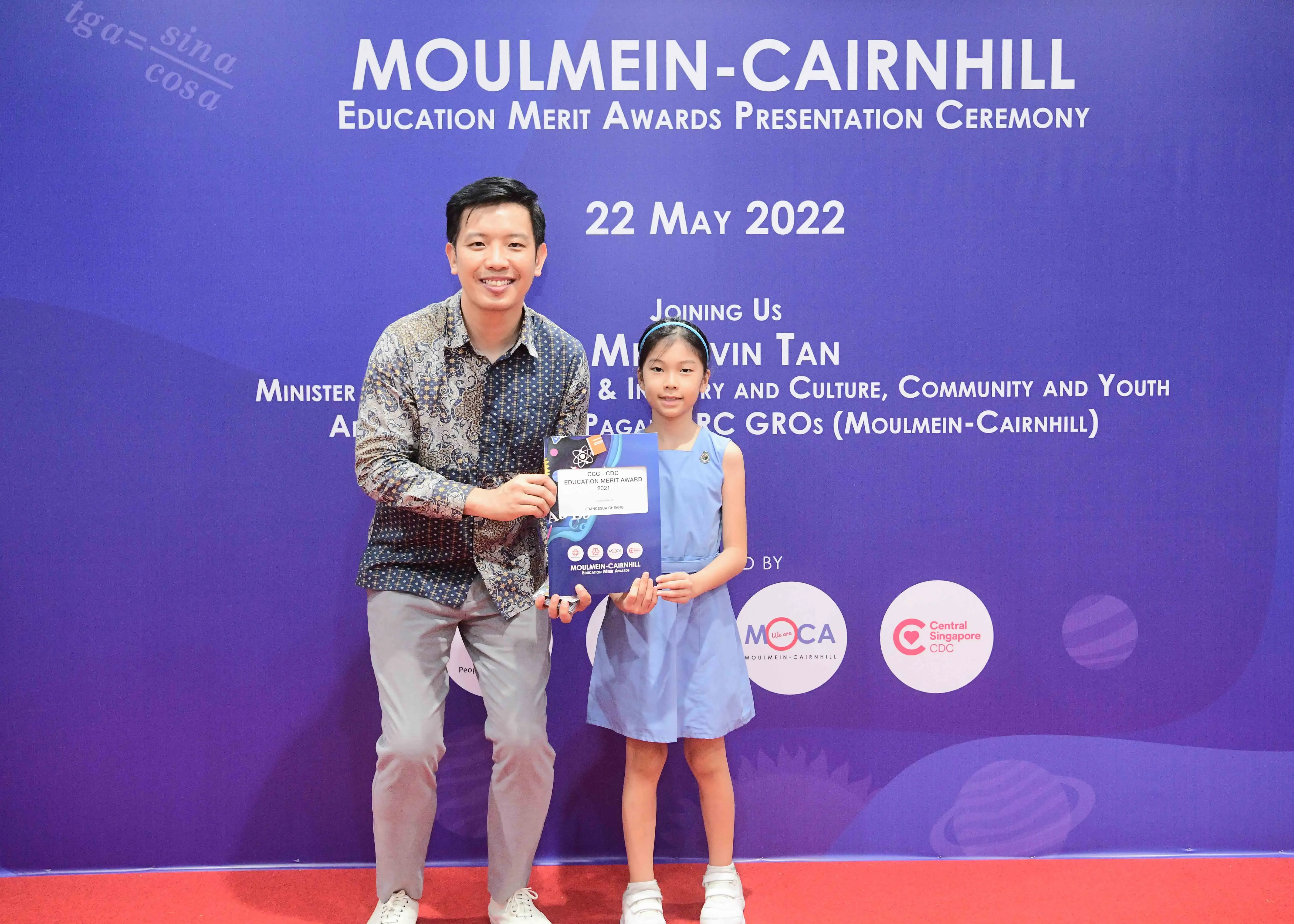 A man and a young girl hold an award at the Moulmein-Cairnhill Education Merit Awards Ceremony on 22 May 2022.