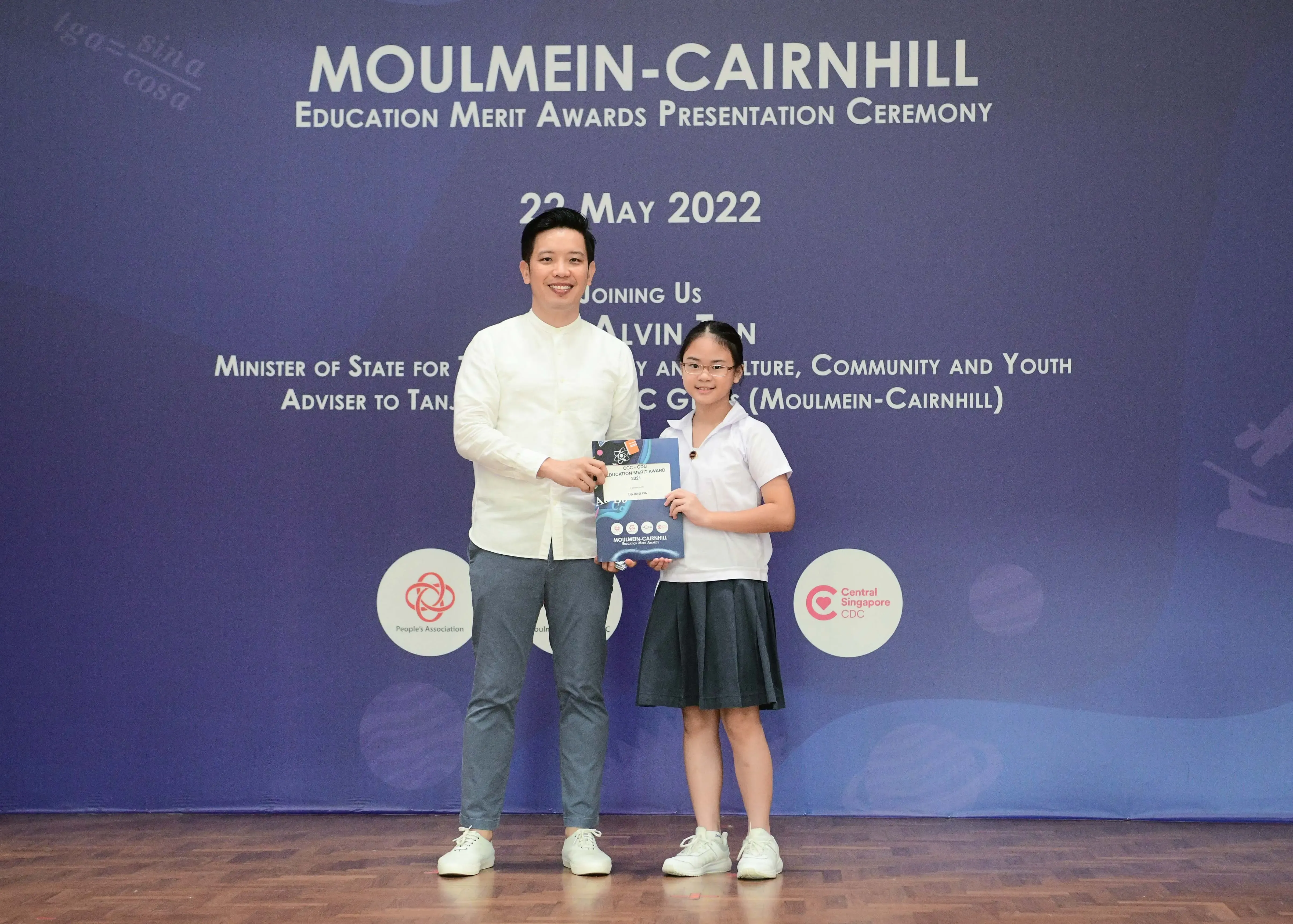 A man and a young girl hold an award together at the Moulmein-Cairnhill Education Merit Awards ceremony on 22 May 2022.